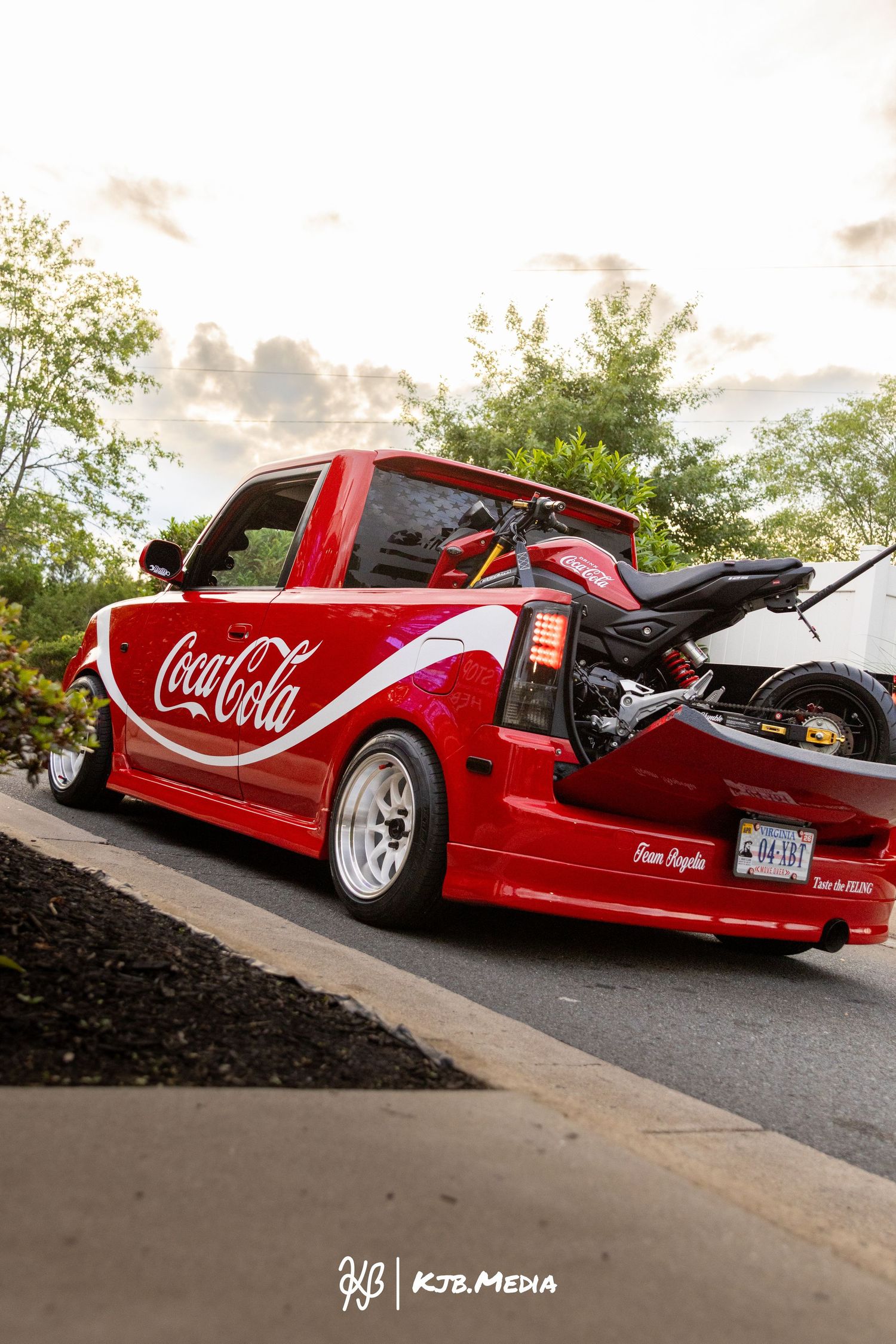 Custom red Coca-Cola themed lowrider truck photographed at sunset against landscaping.
