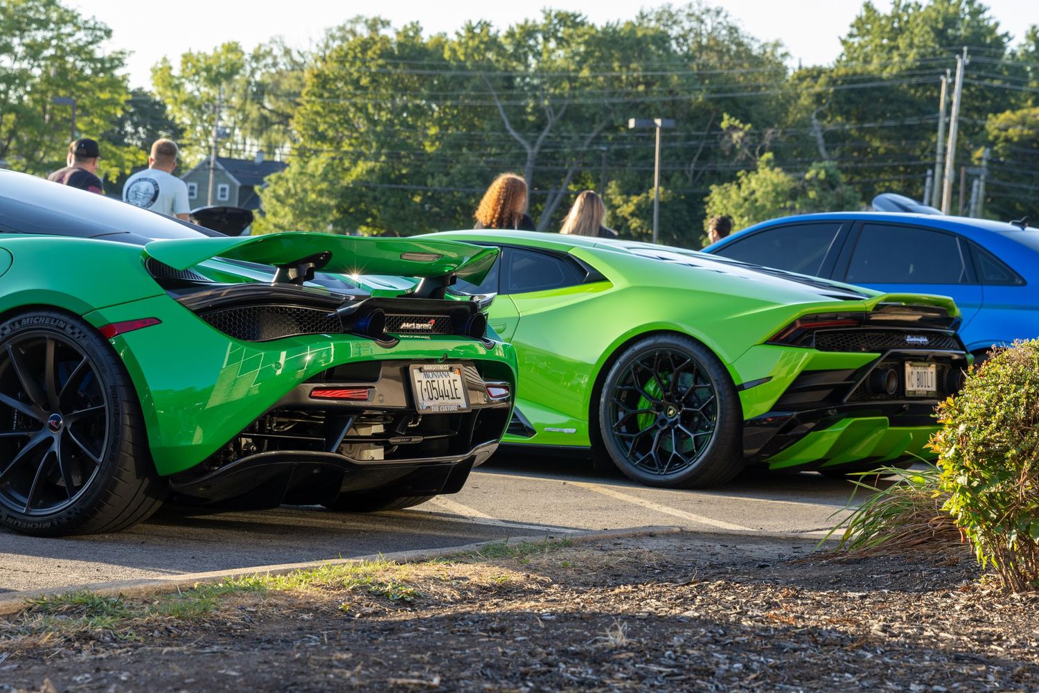 A row of luxury sports cars including Lamborghinis in vibrant colors displayed outdoors during a sunny day.