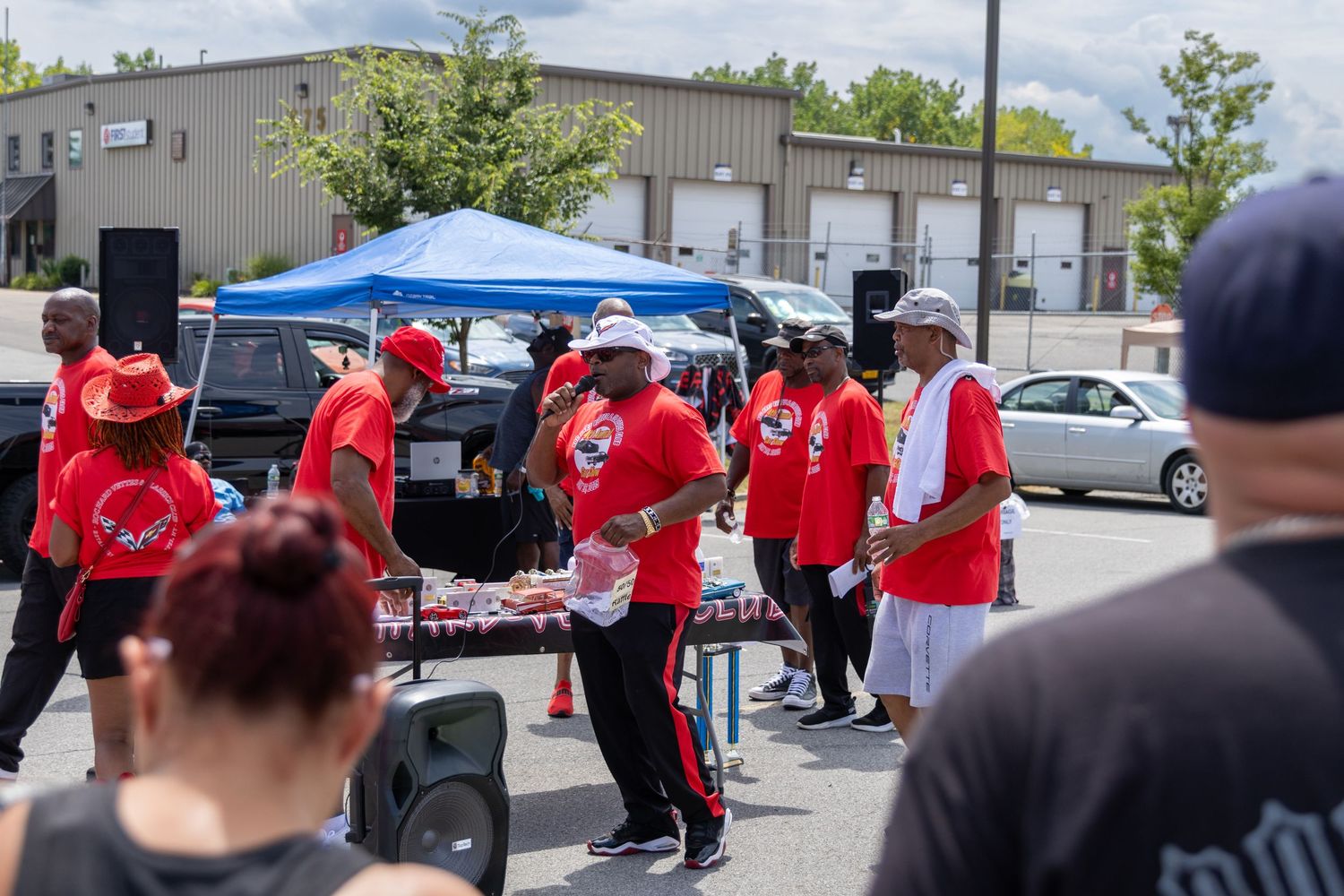 Group of people in red shirts stand together outdoors during what appears to be a community gathering or event.