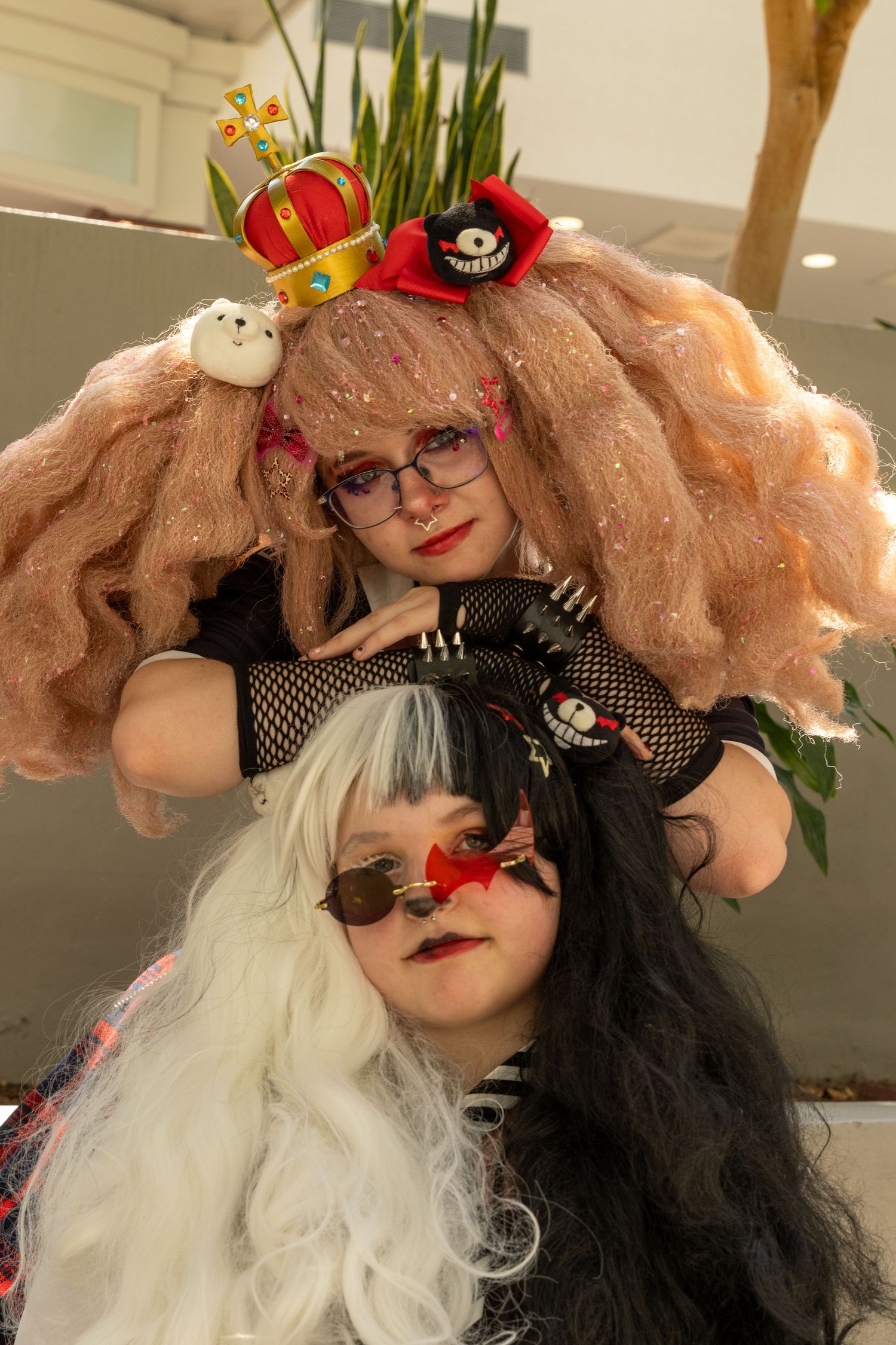 Artistic portrait showing split black and white wig with fishnet details and pink crown hair accessory.