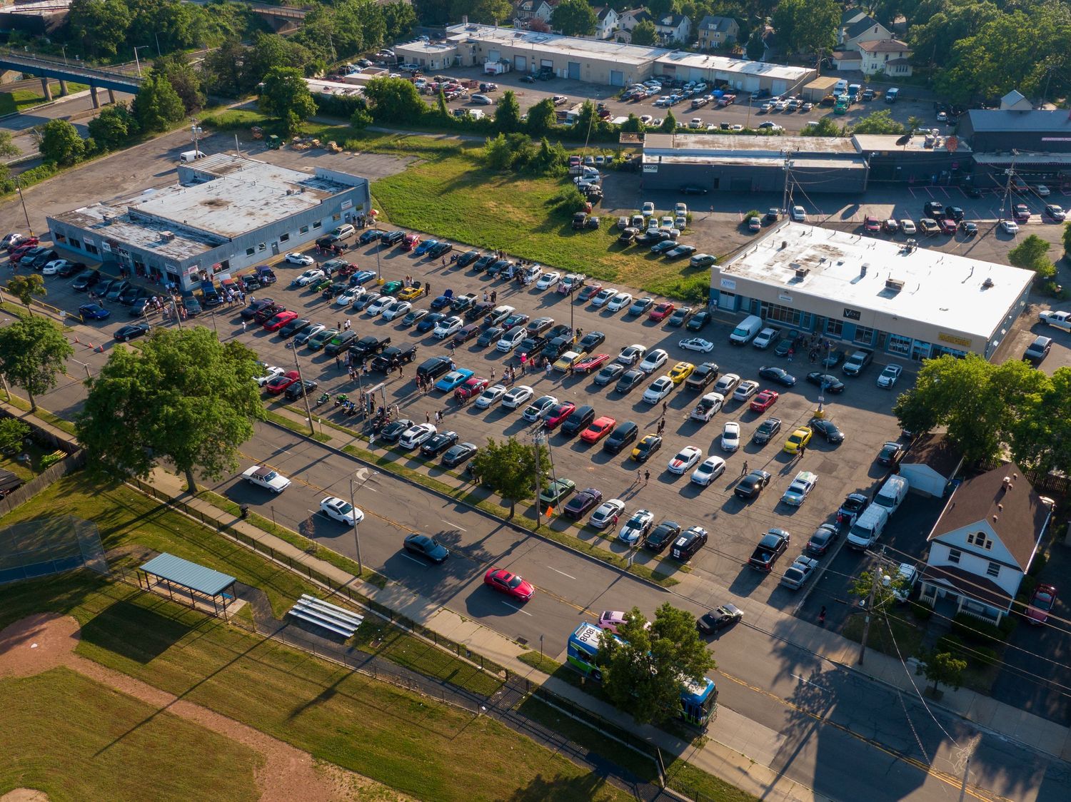 Aerial view of commercial parking lots and buildings surrounded by green spaces during daytime.