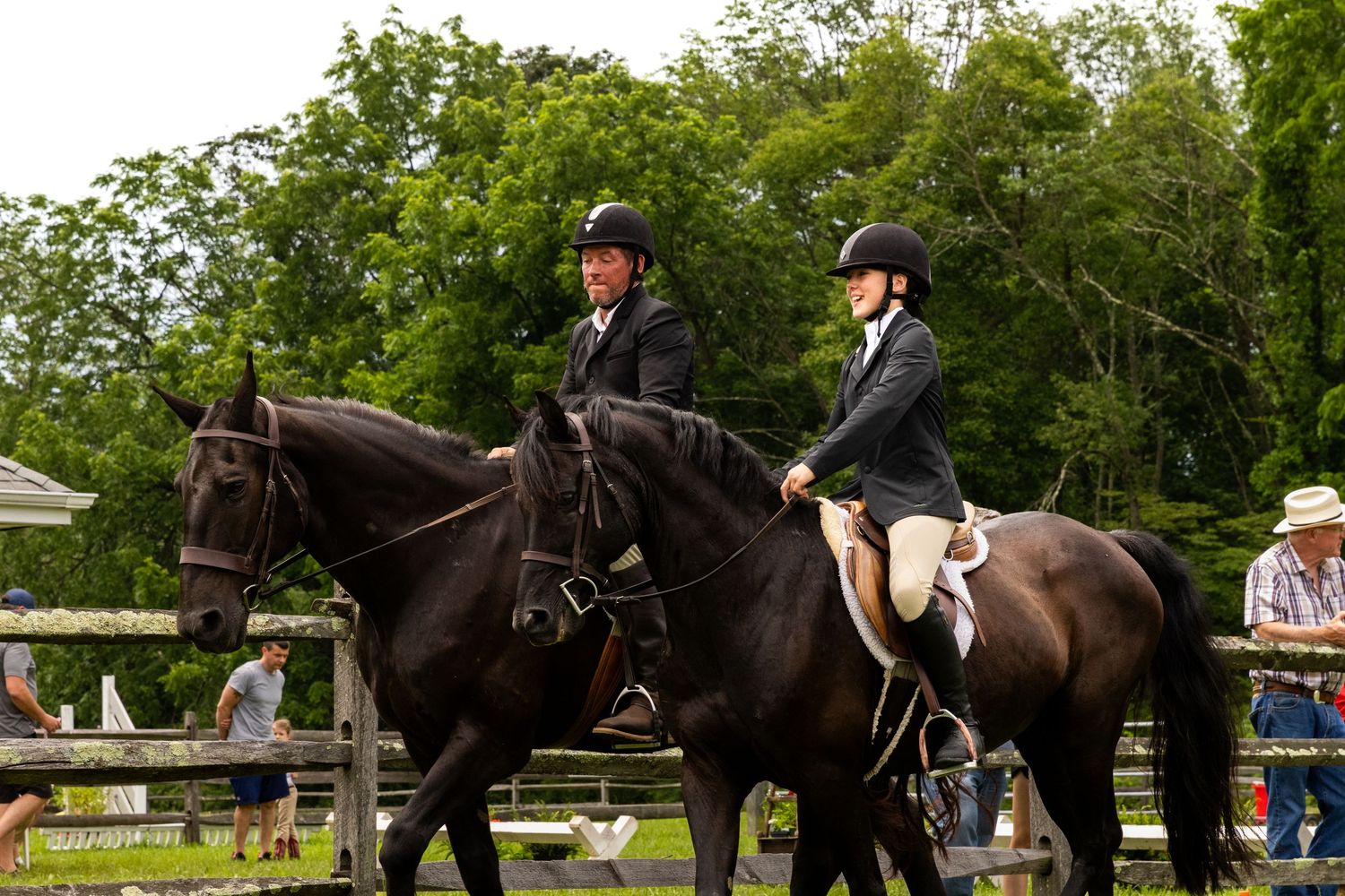 Two riders in formal attire guide their horses during an equestrian competition.