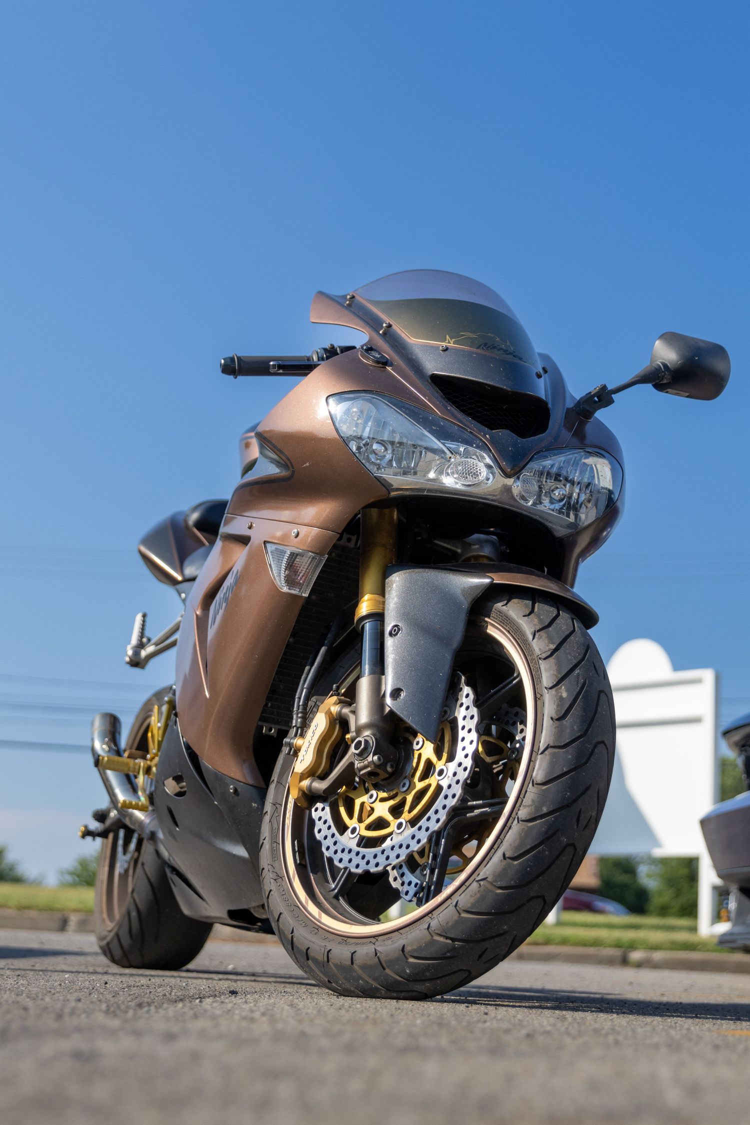 Bronze Kawasaki sport bike with gold accents photographed from low angle.