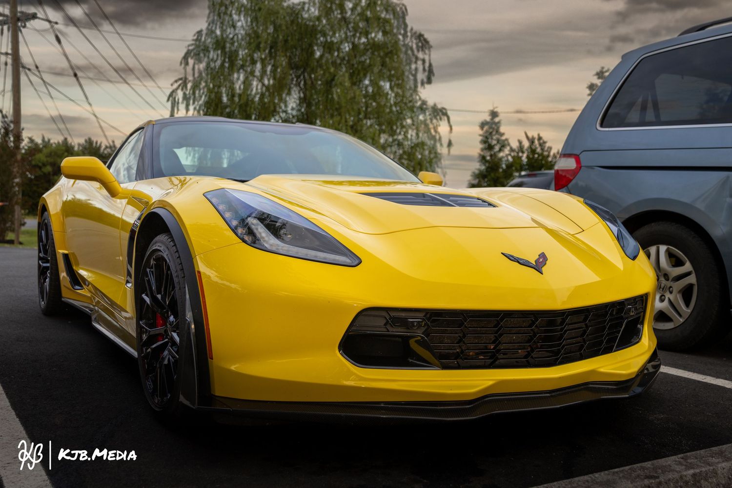 Yellow Chevrolet Corvette captured at sunset with dramatic lighting and trees in background.