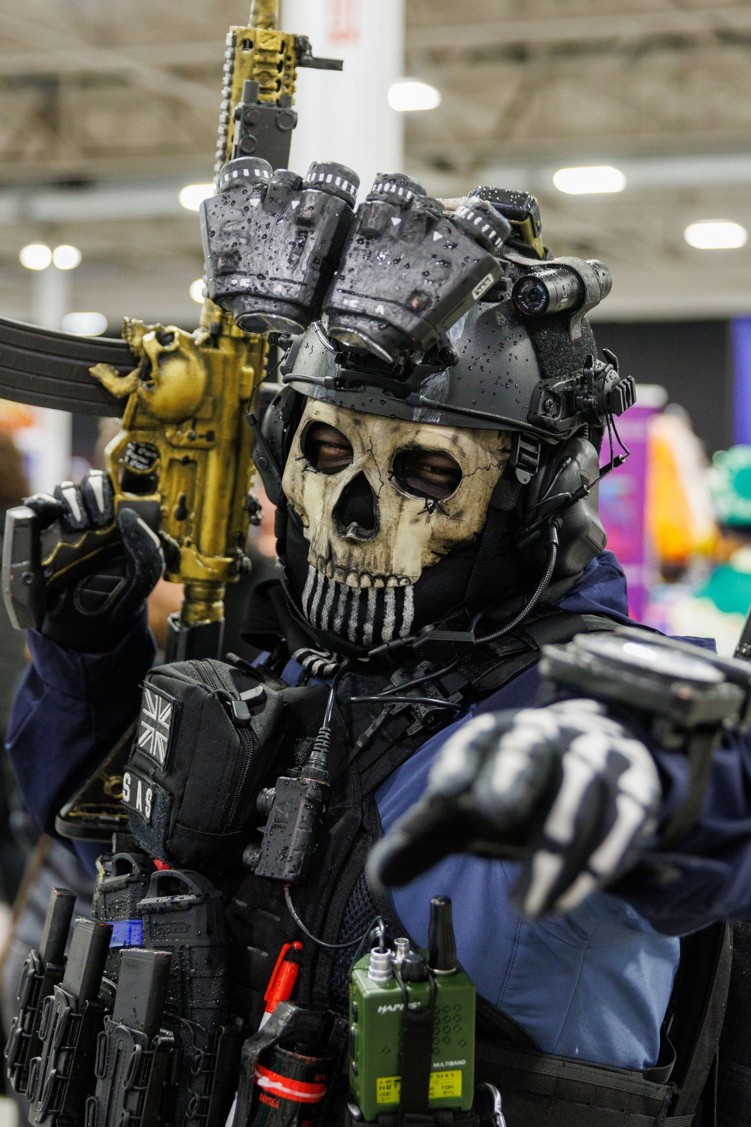 Detailed Call of Duty Ghost cosplay with skull mask, tactical gear, and gold weapon at a comic convention.