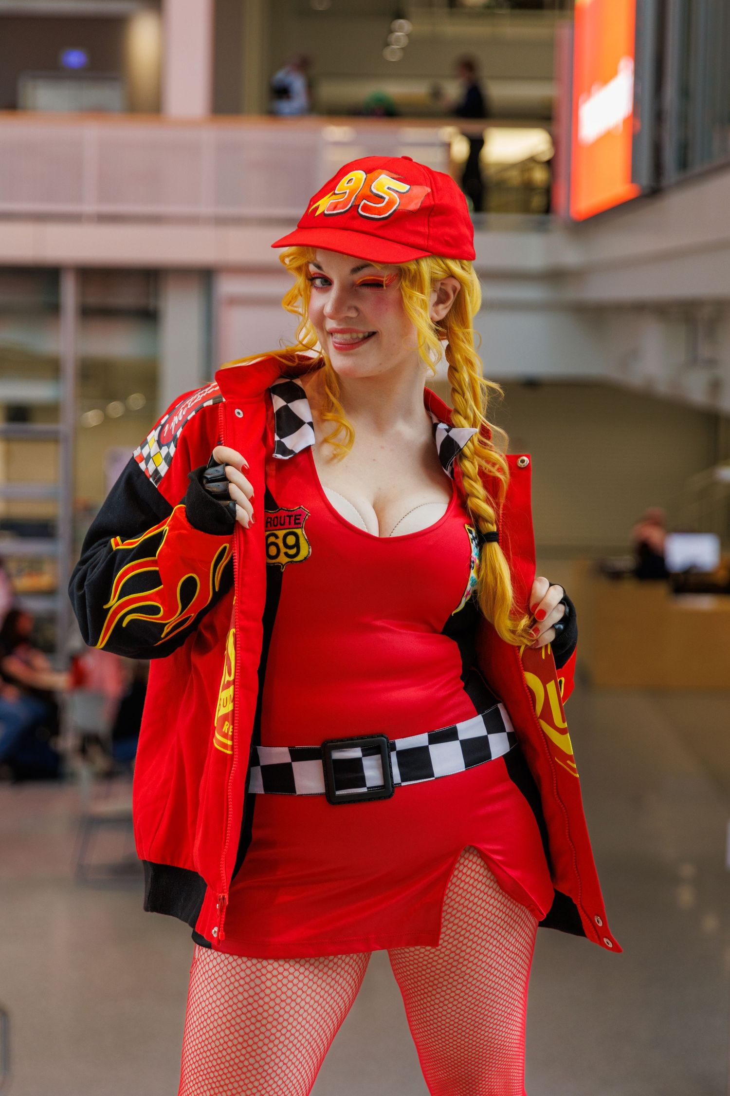 Cosplayer dressed as Lightning McQueen in red racing outfit with checkered belt and number 95 cap at convention.