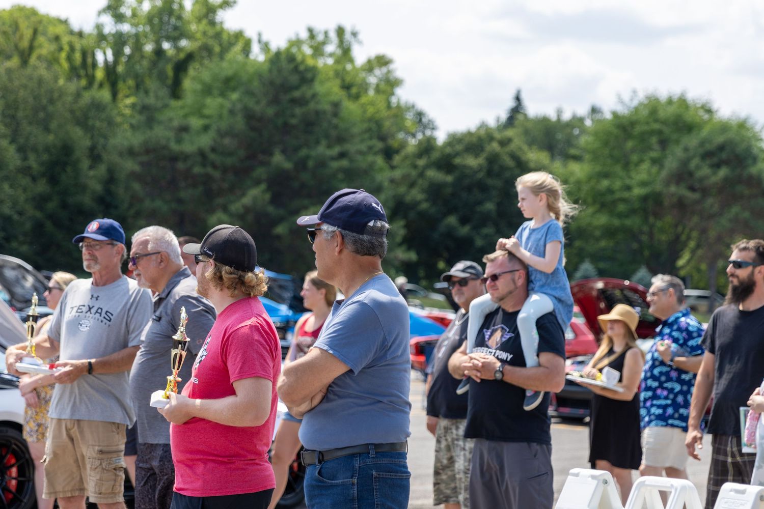 People line up outdoors as they look through telescopes and eclipse glasses to view a solar event.