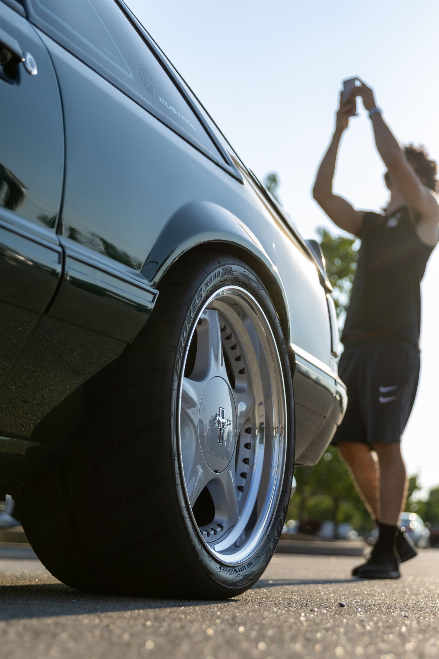 Close-up shots of a lowered car with stretched tires and custom alloy wheels parked on asphalt.