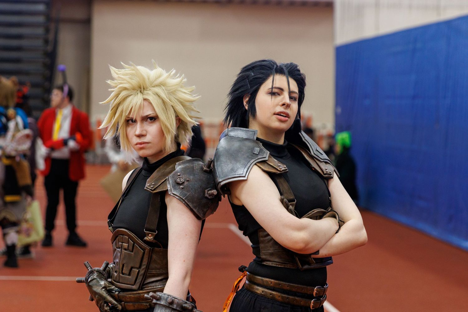 Two cosplayers dressed as Final Fantasy VII characters Cloud and Vincent Valentine pose back-to-back at a convention.