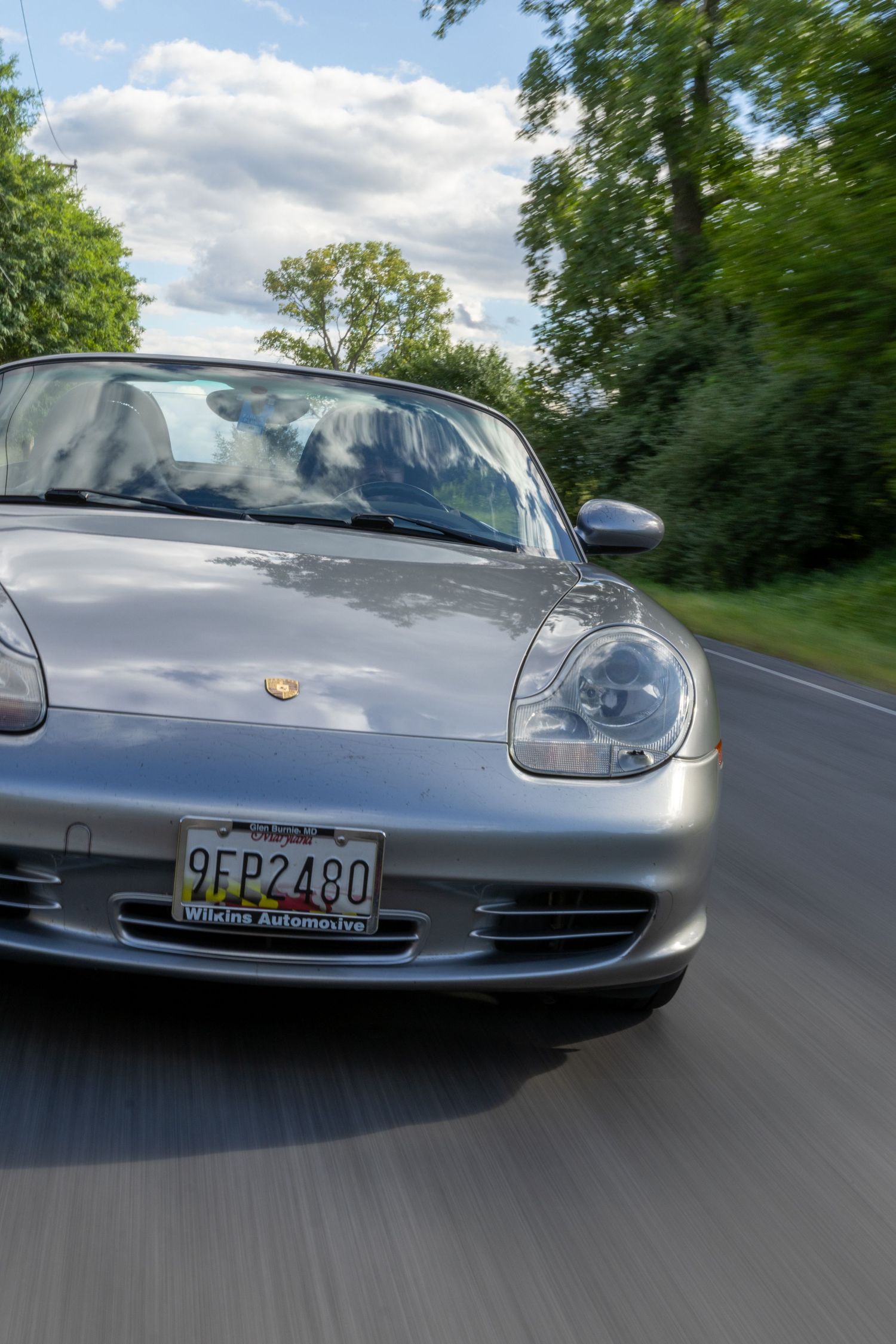 Dynamic driving shots of a silver Porsche sports car photographed from multiple angles on a winding forest road.