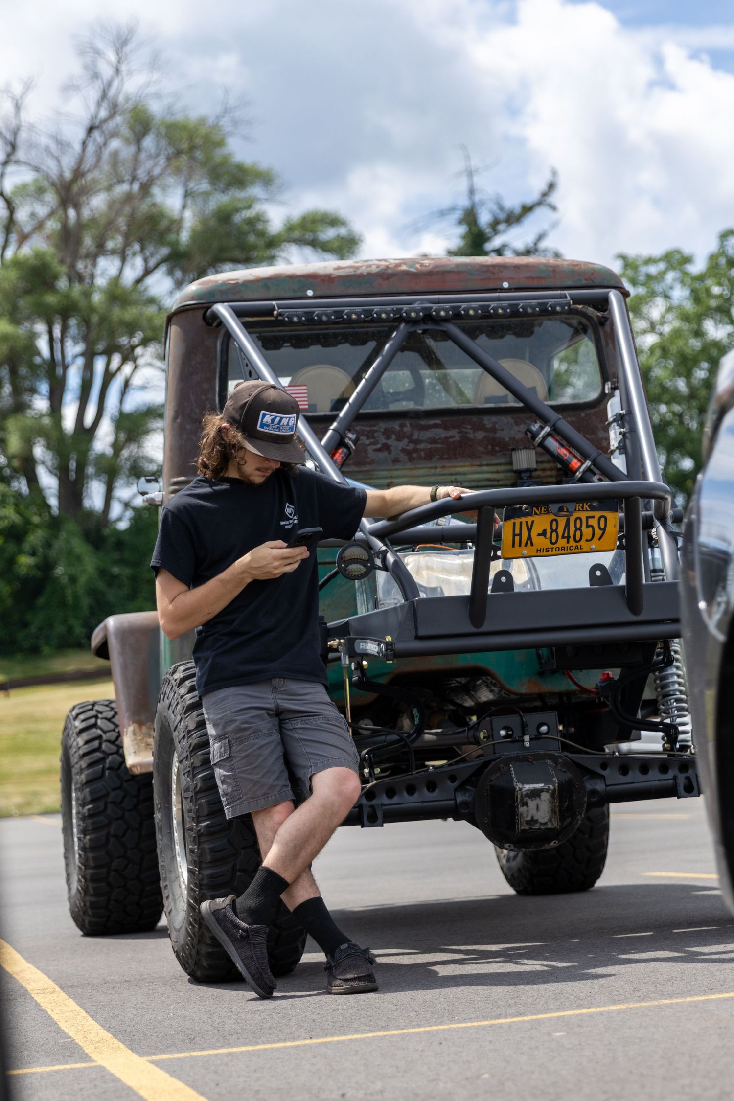 Series of four sequential photos showing someone checking and inspecting a lifted off-road vehicle in a parking lot.
