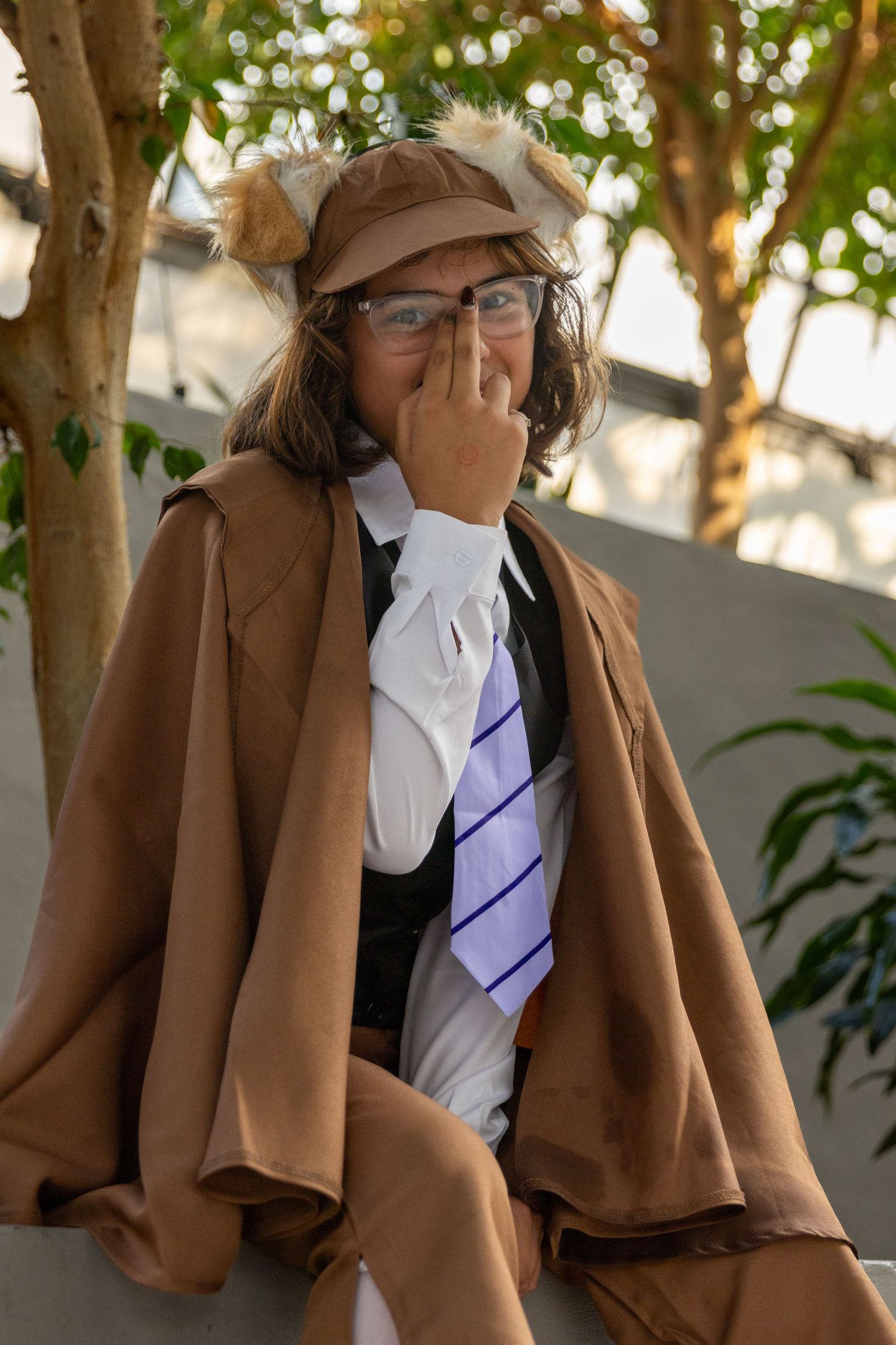 Multiple images show someone wearing a brown blazer with a white shirt and striped tie outdoors on a sunny day.