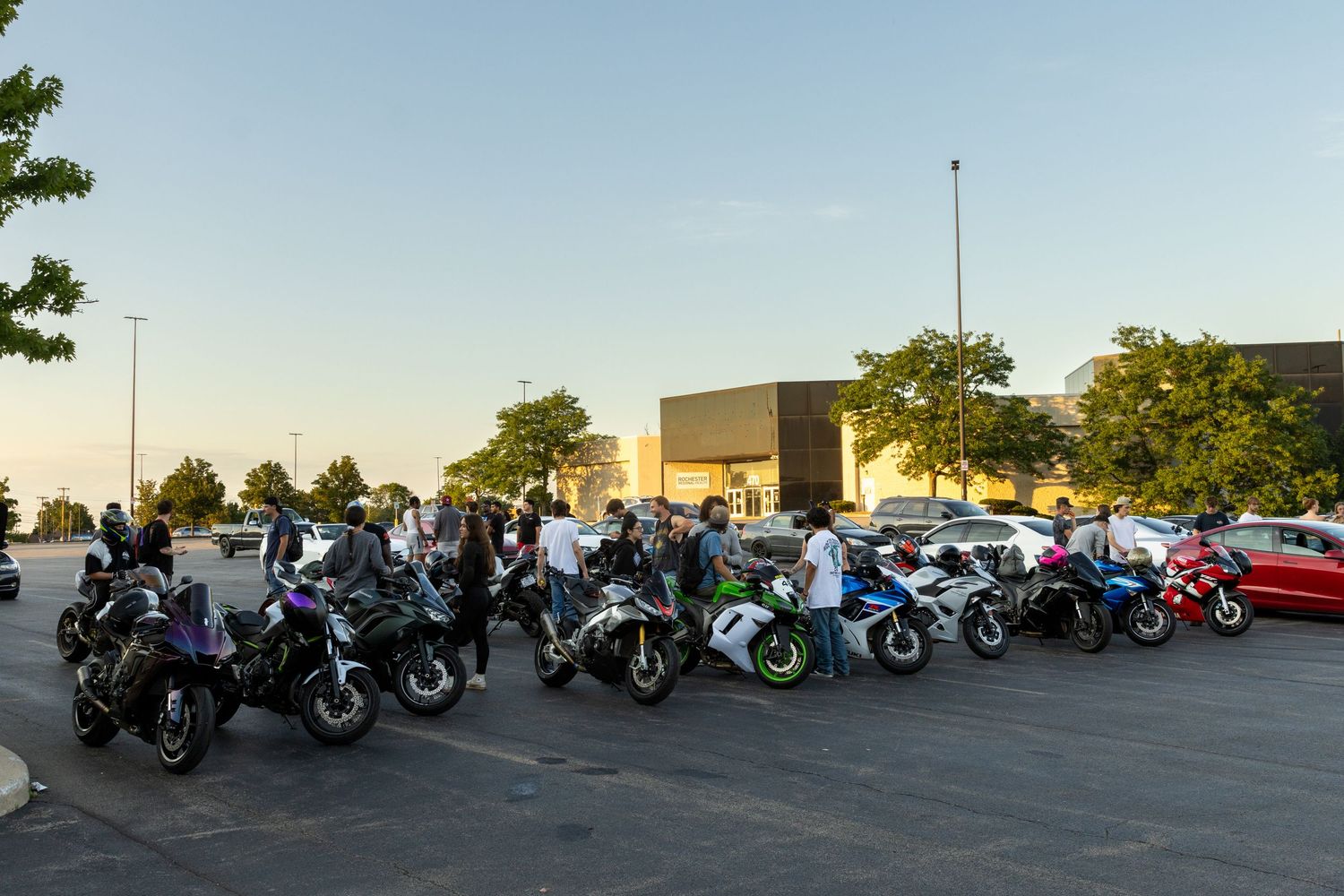 A long row of motorcycles parked in a line at sunset, showing diverse types of sport bikes and cruisers.