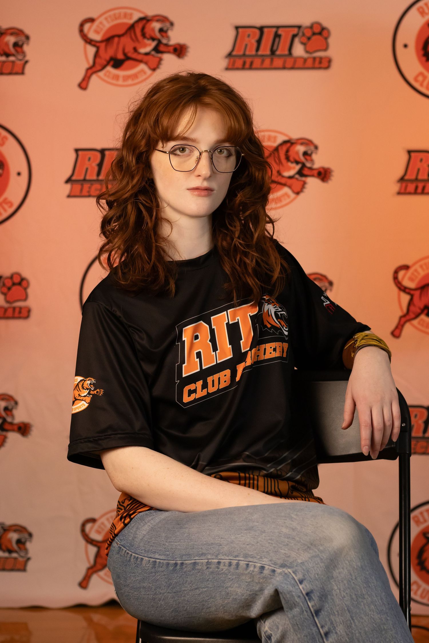 RIT Club member poses against orange backdrop with tiger logo.