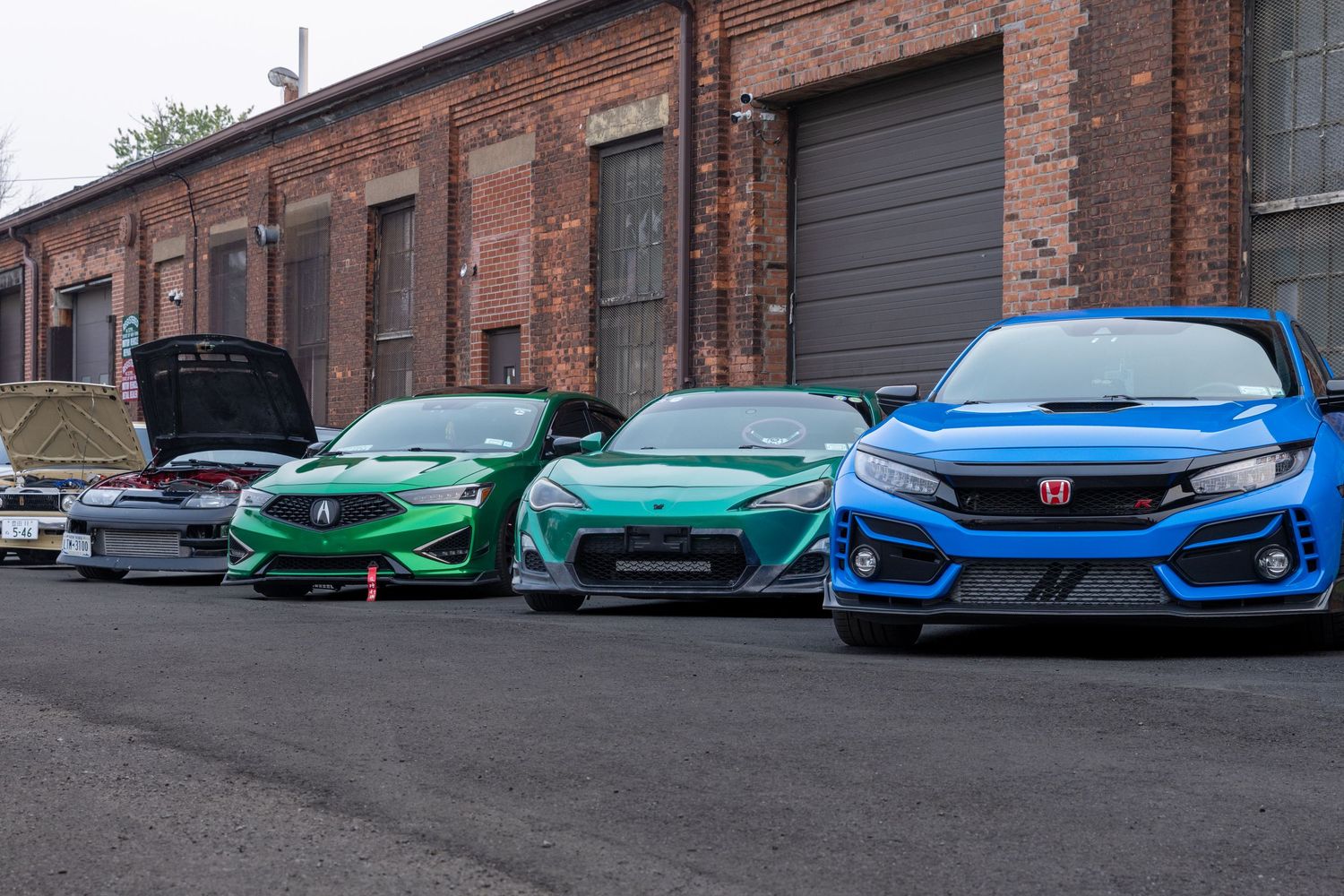 Several colorful sports cars including a Lamborghini Aventador line up in a factory or showroom setting.