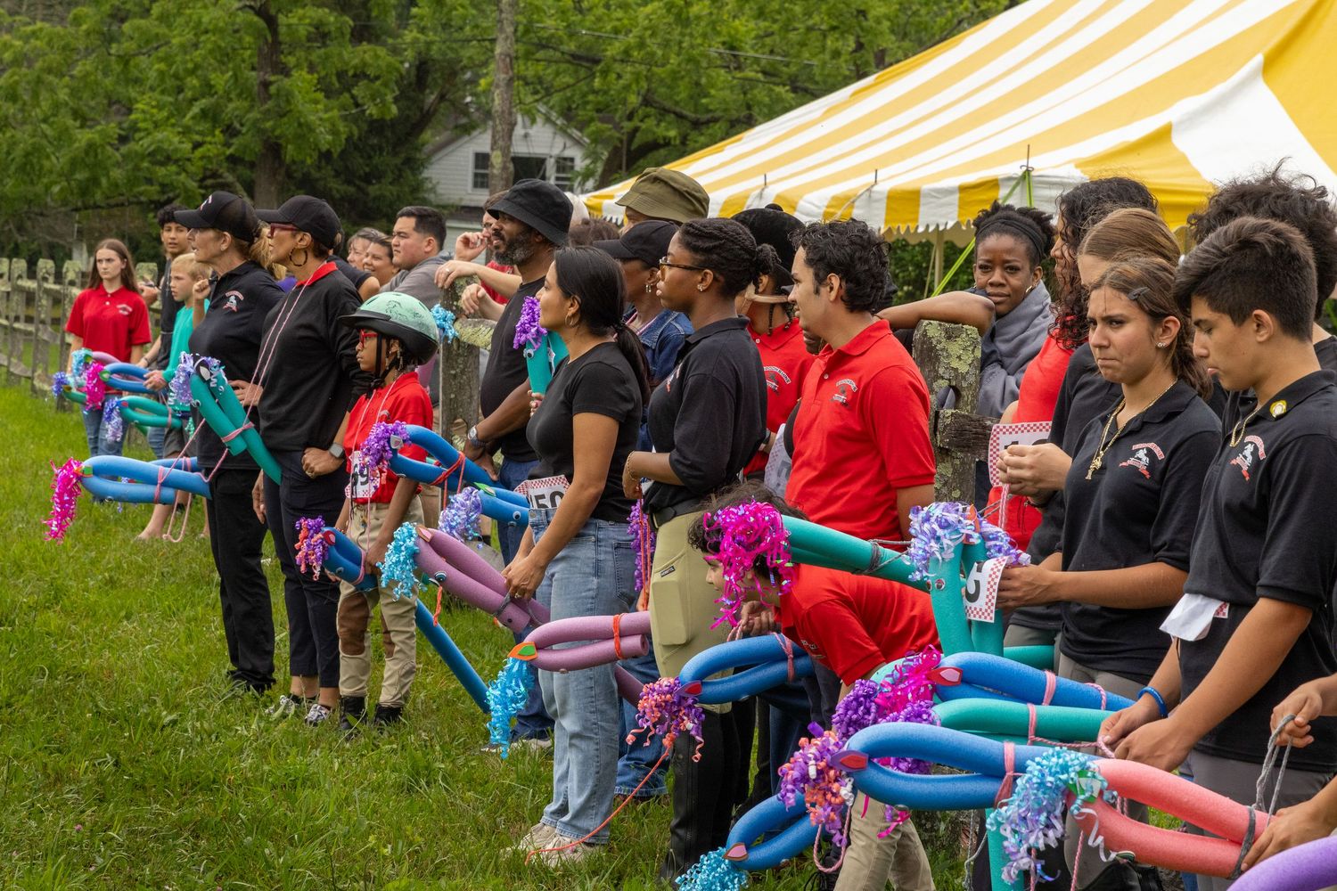 A line of people holding colorful blankets at an outdoor event.