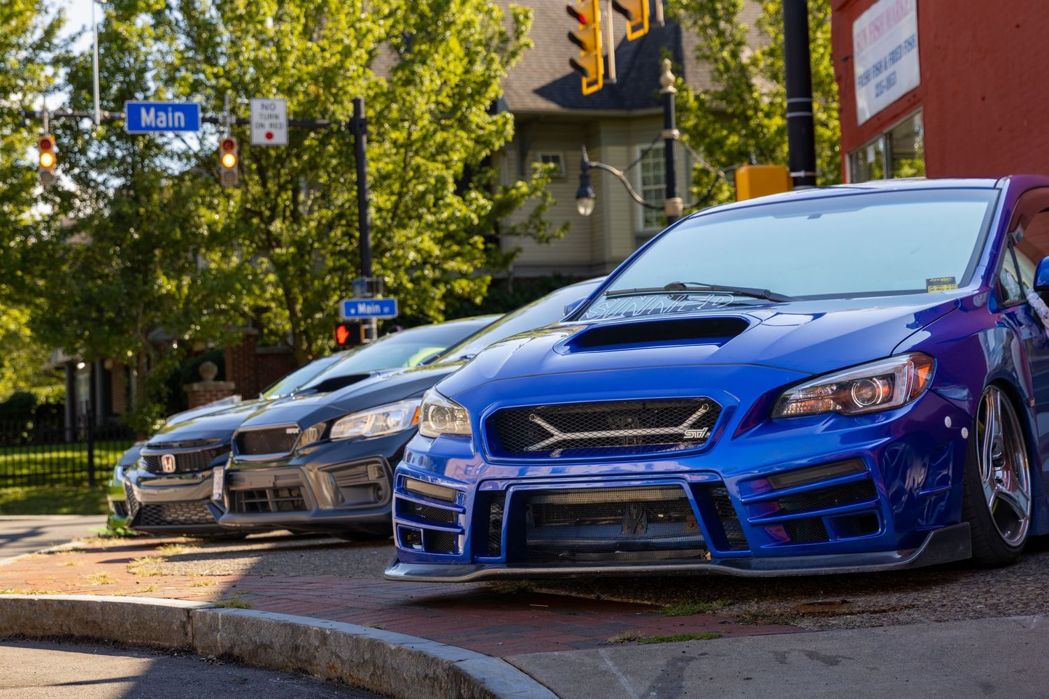 A lineup of blue Subaru WRX and STI performance cars parked in a row showing their distinctive front ends.