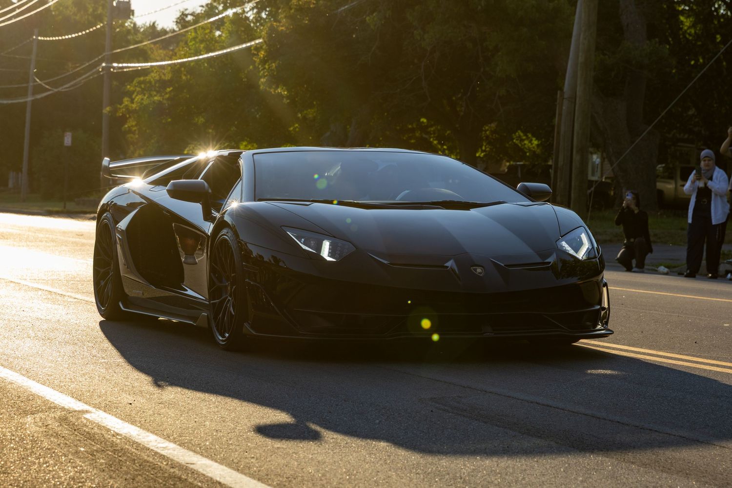 Multiple high-performance Lamborghini supercars parked in a line at a car meet showing various angles and colors.