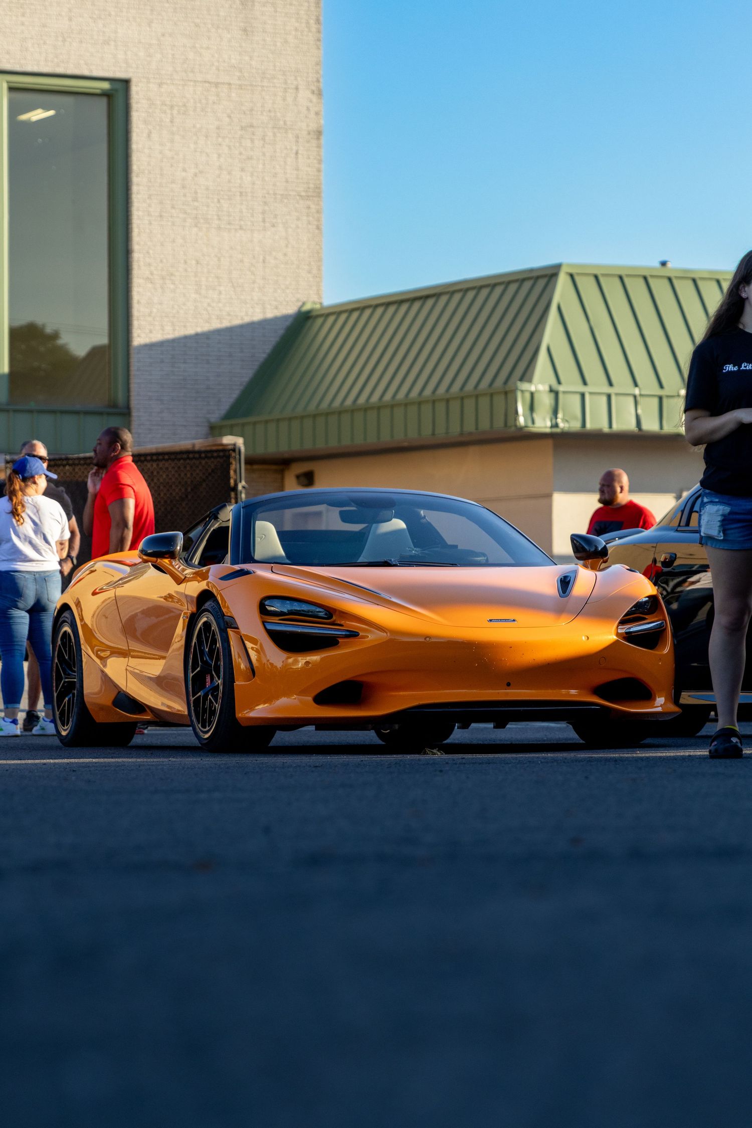 Orange McLaren 720S supercar parked outside a building during sunset.