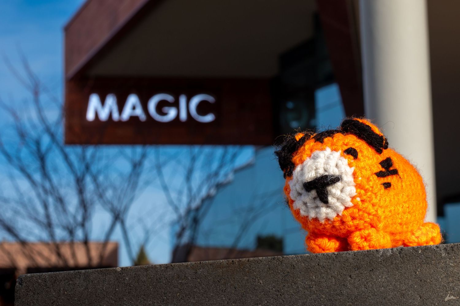 Orange plush tiger figure sits in front of sign reading MAGIC.