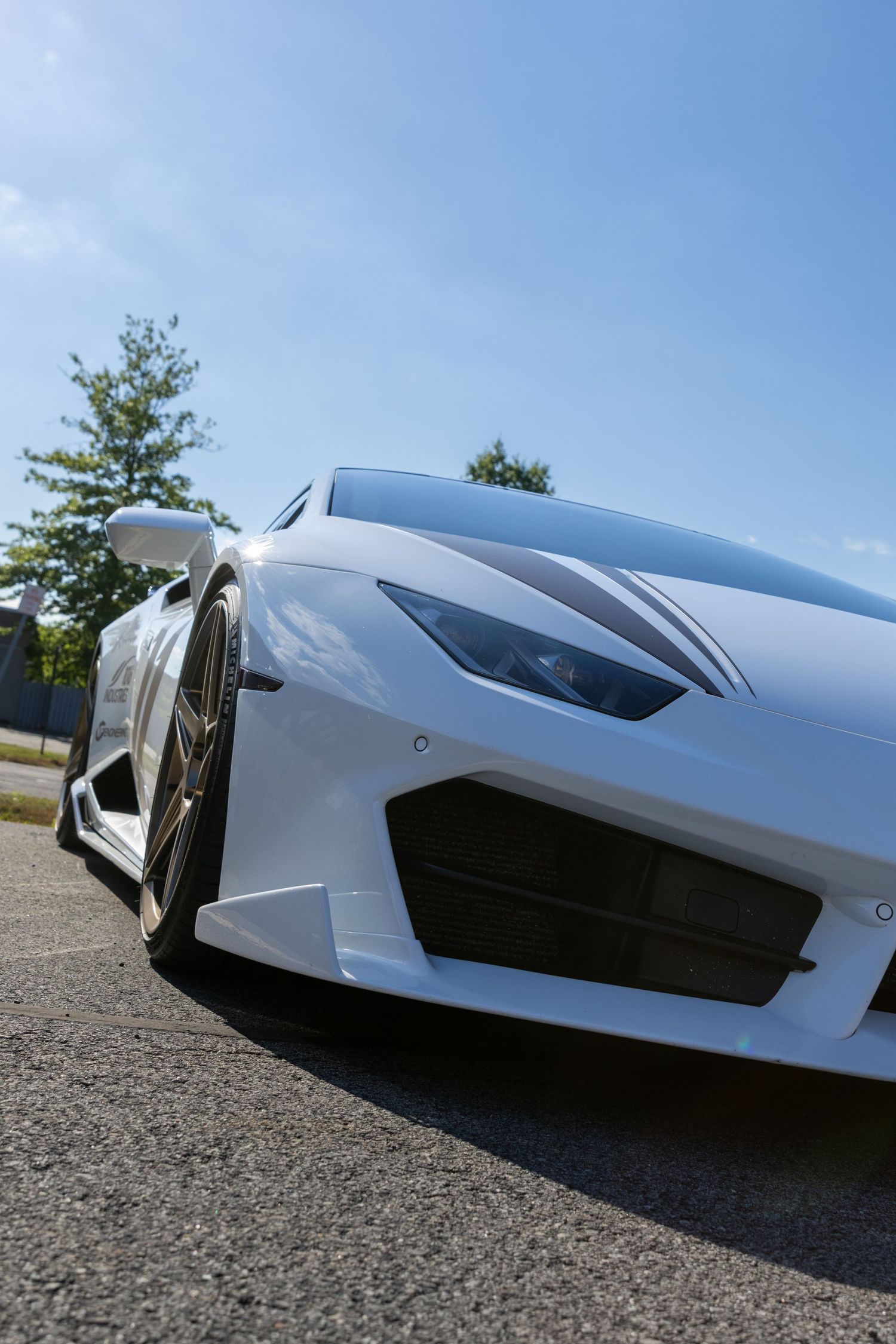 Close-up views of a sleek white concept car's aerodynamic body panels and curves against a blue sky background.