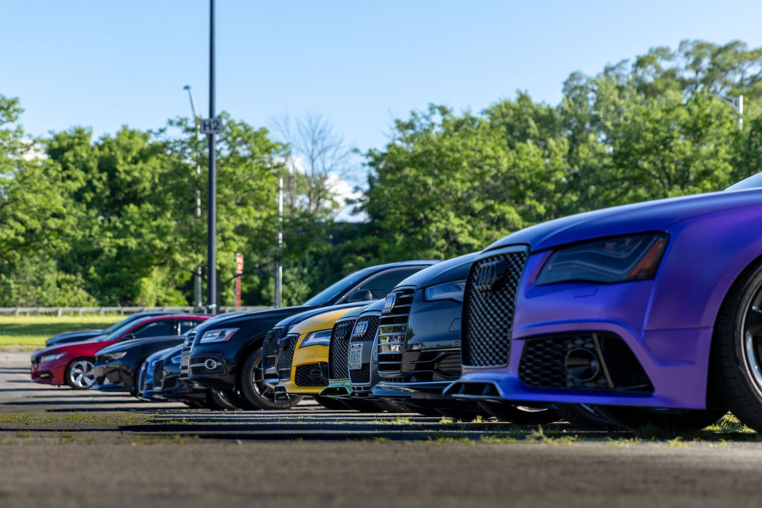 Row of colorful high-performance cars lined up at an outdoor event.