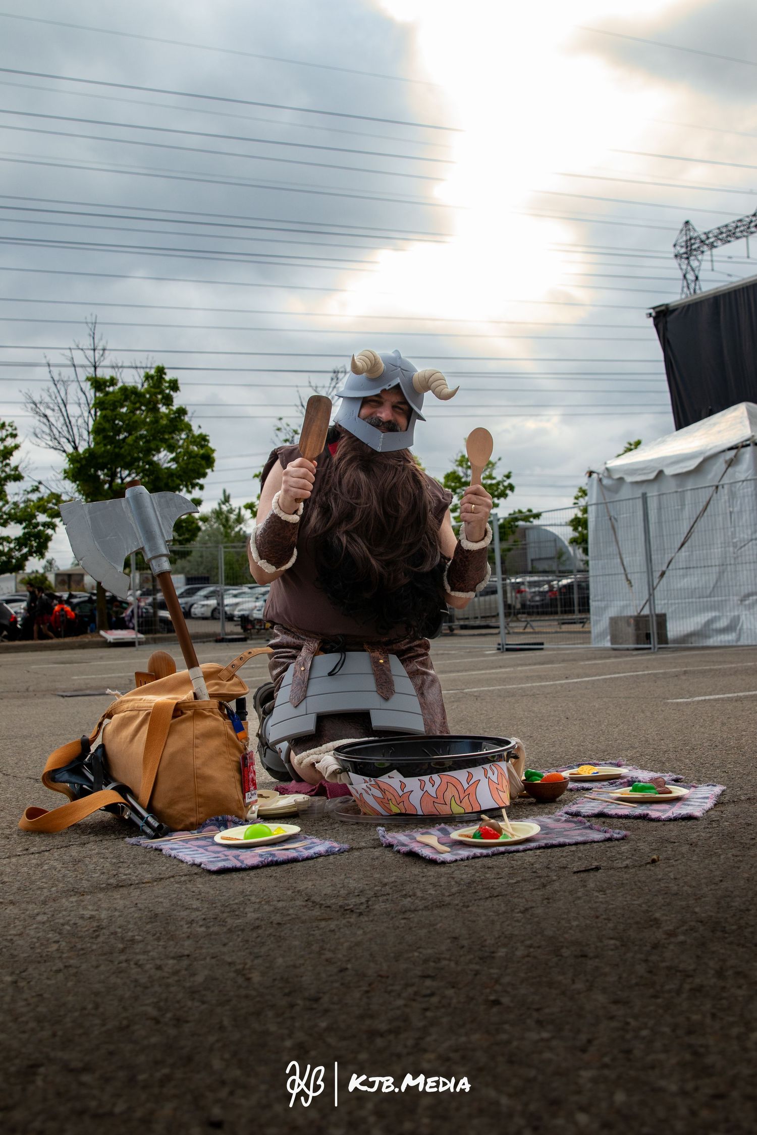 Cosplayer in viking attire displaying merchandise on a blanket at an outdoor event.