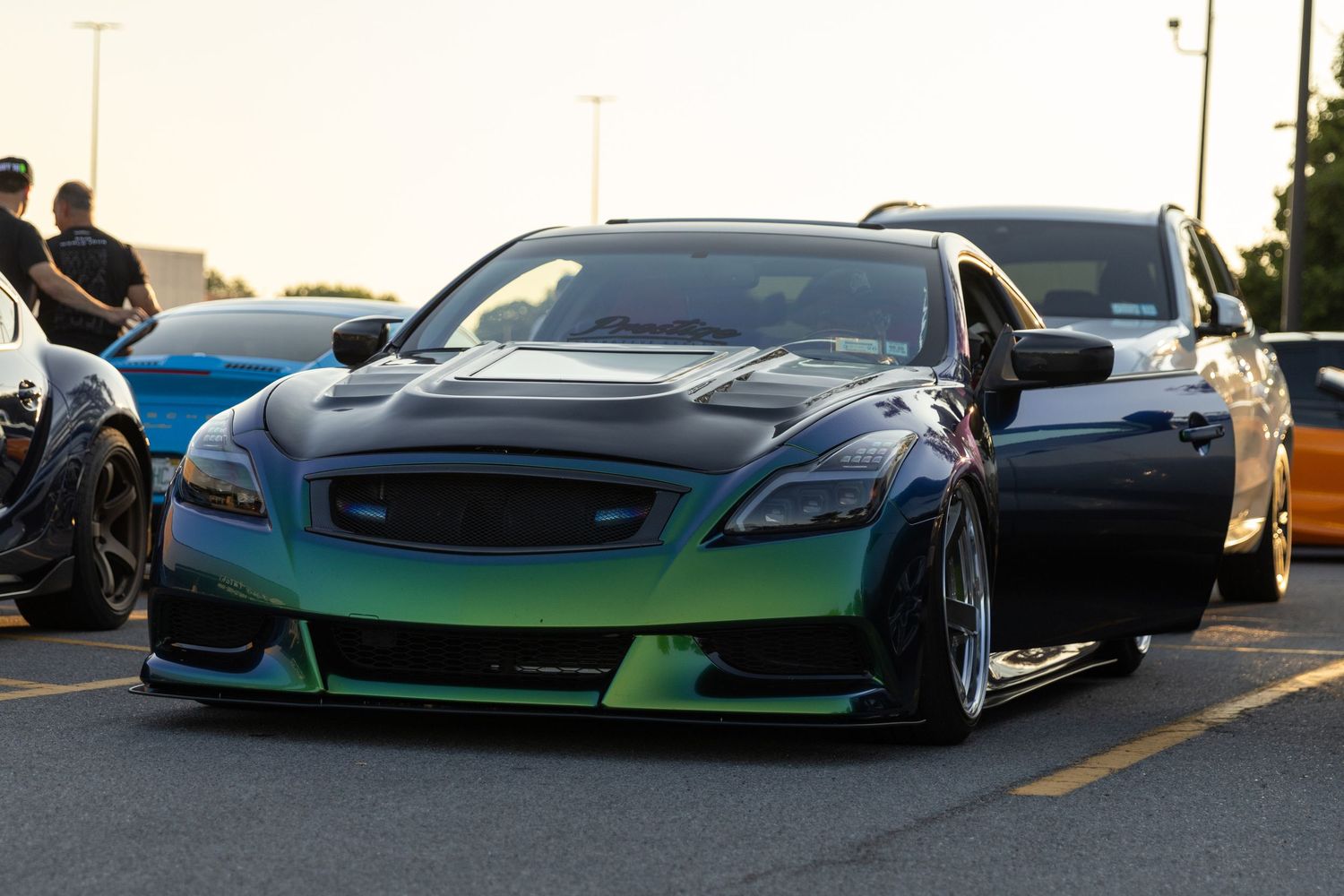 Modified teal sports car with aggressive bodywork and lowered suspension in a parking lot.