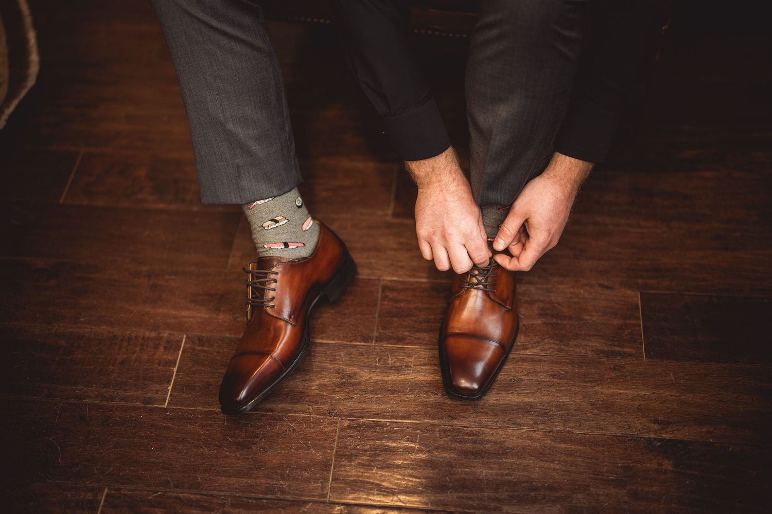 Brown leather dress shoes on a hardwood floor during a formal event.