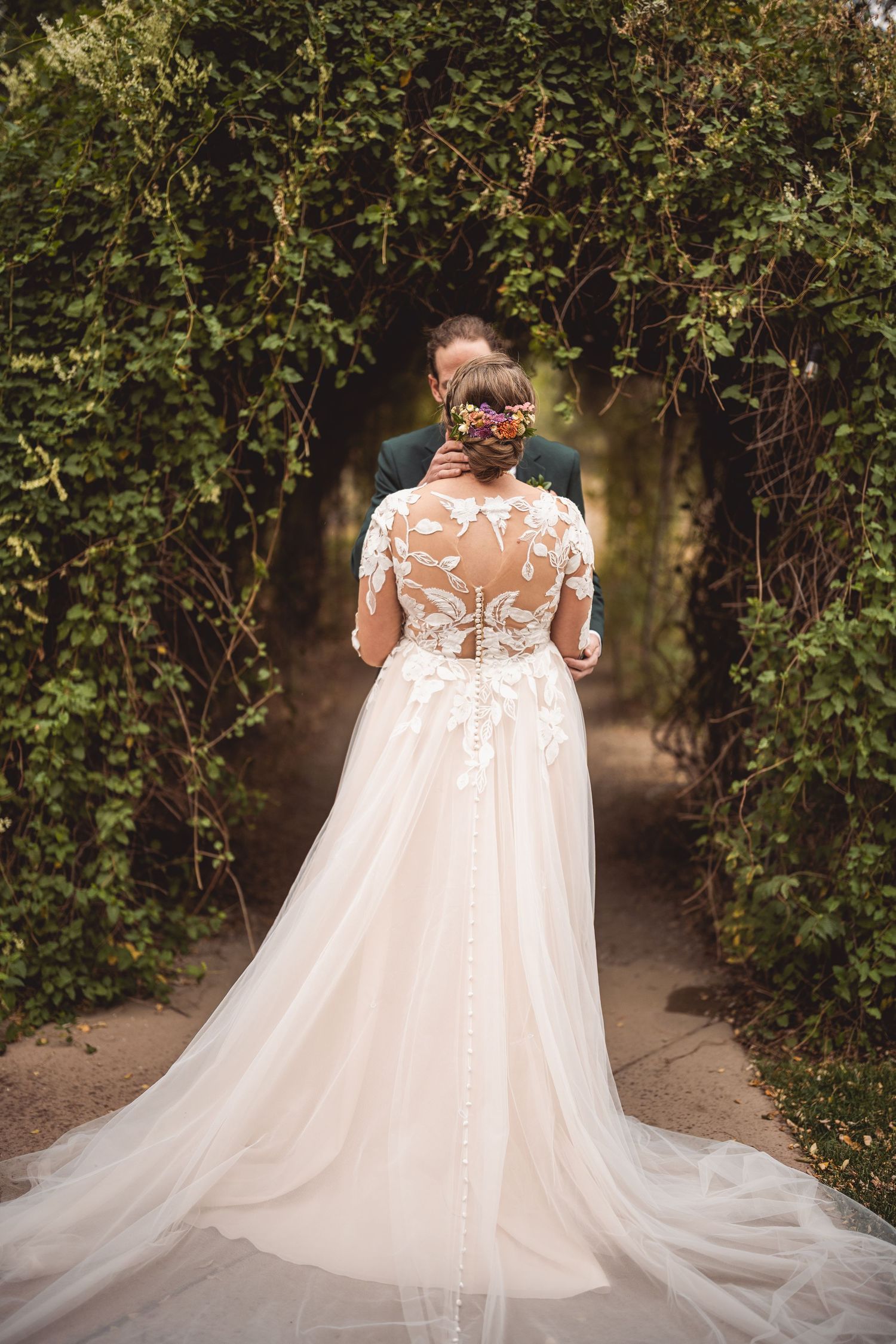 Beautiful wedding dress with lace details and flowing train showcased in garden setting.