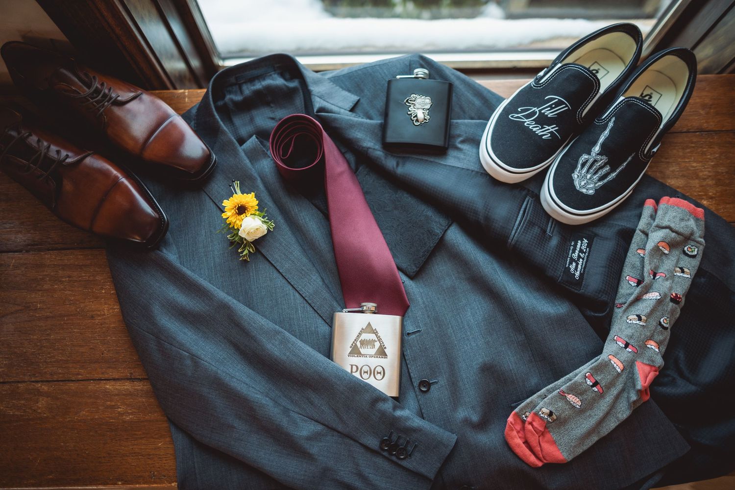 Wedding accessories including dress shoes, ties, and boutonnieres arranged on dark wood.