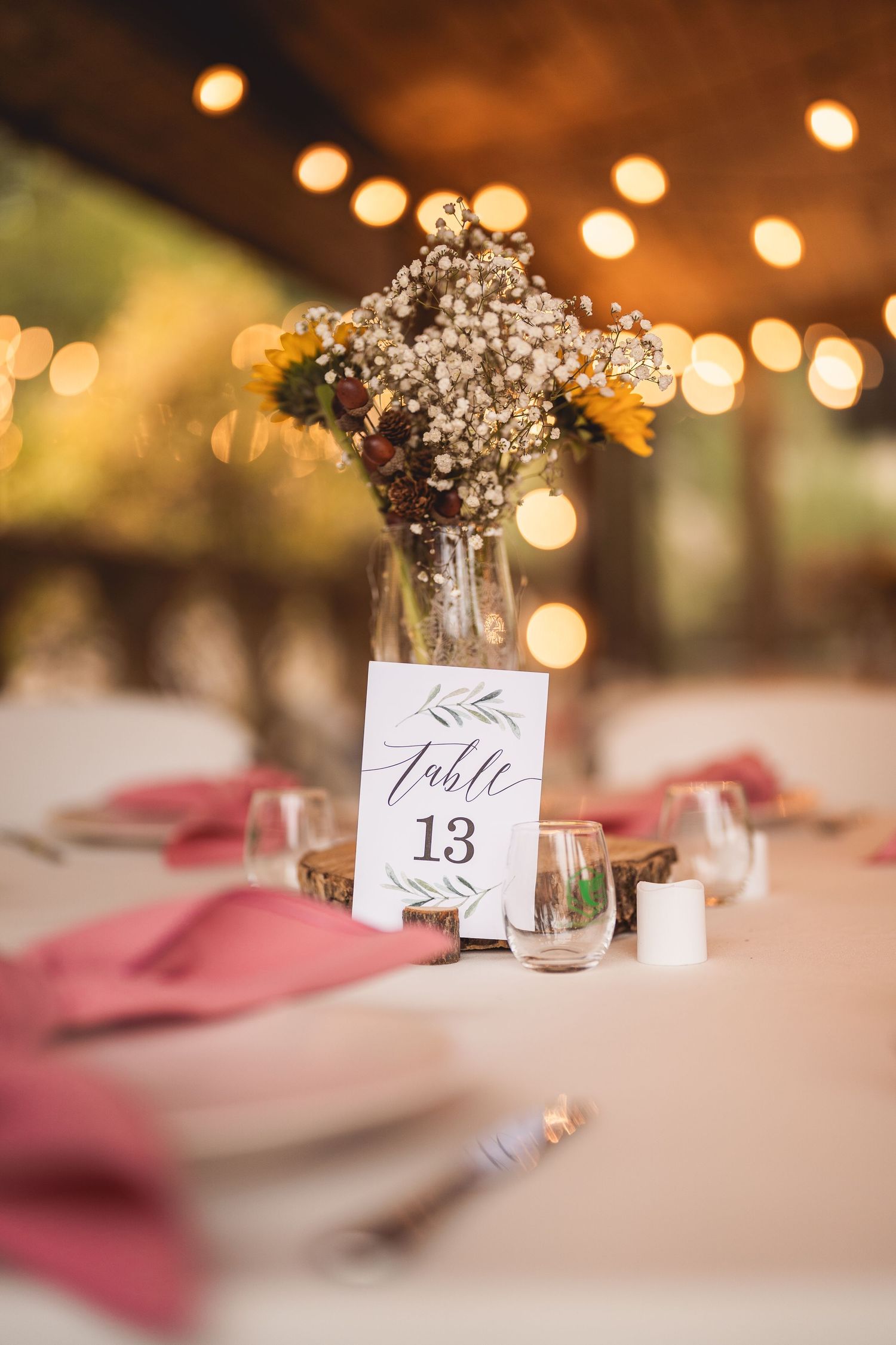 Wedding reception table details with soft lighting, pink napkins and delicate baby's breath centerpieces.