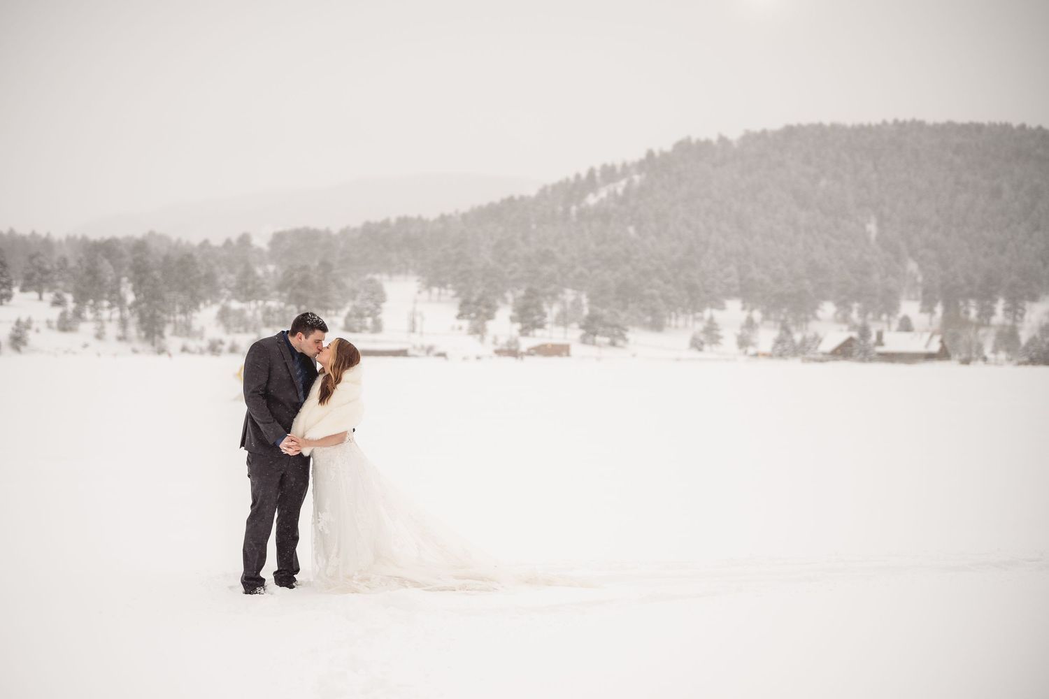 Winter engagement session in snowy landscape with mountains in background.