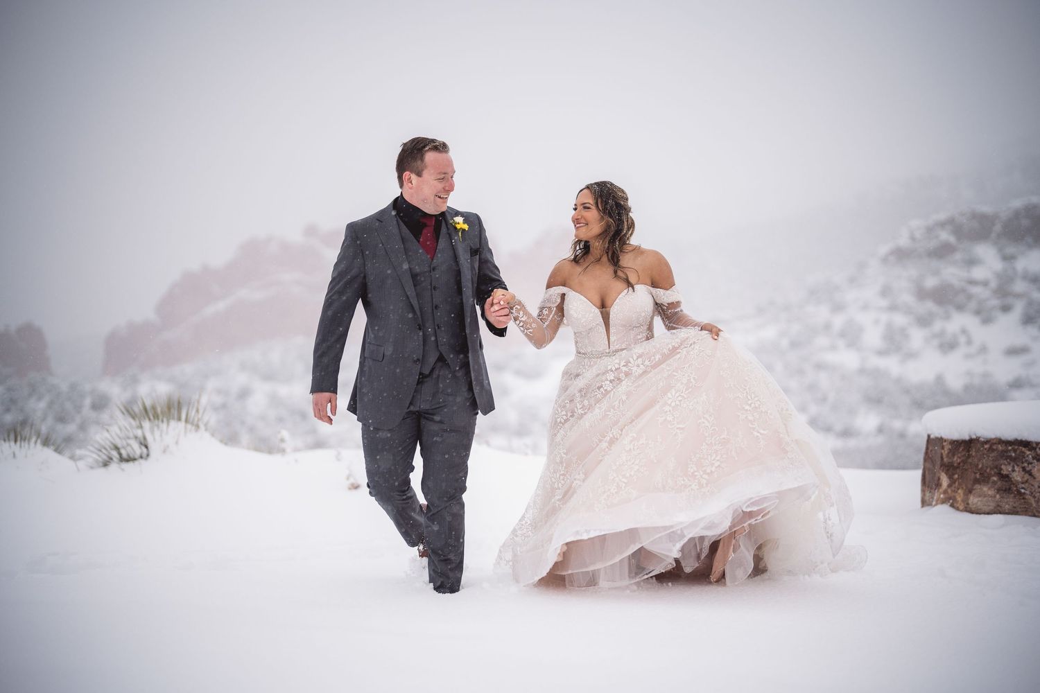 A romantic winter wedding photo shoot with a couple posing in the snow surrounded by evergreen trees.
