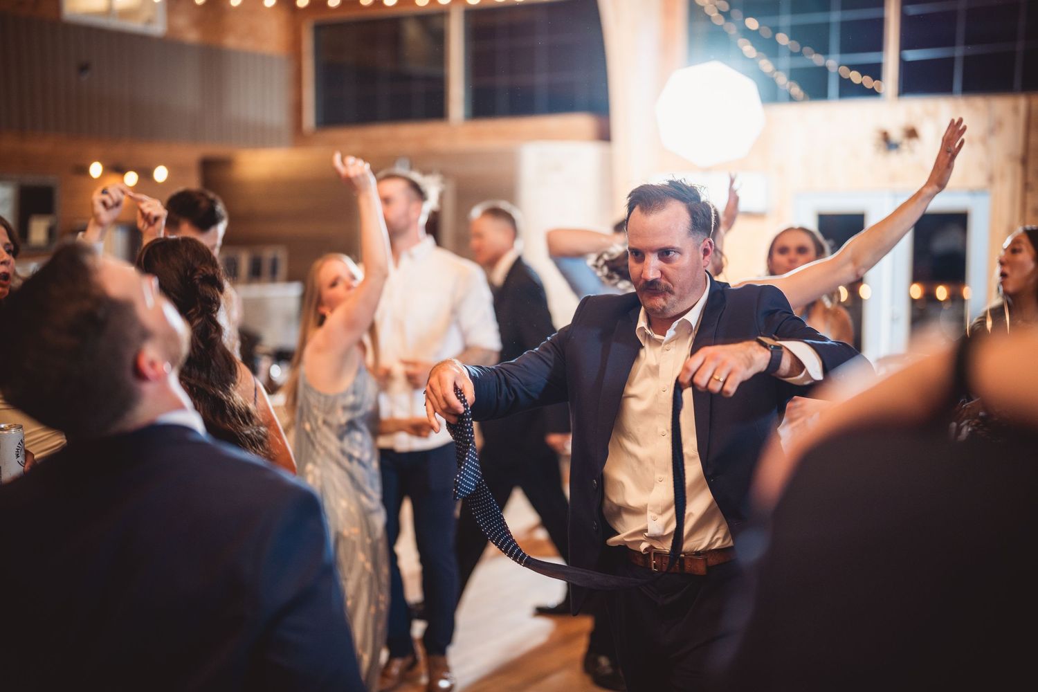 Lively dance floor at a wedding reception with guests celebrating.