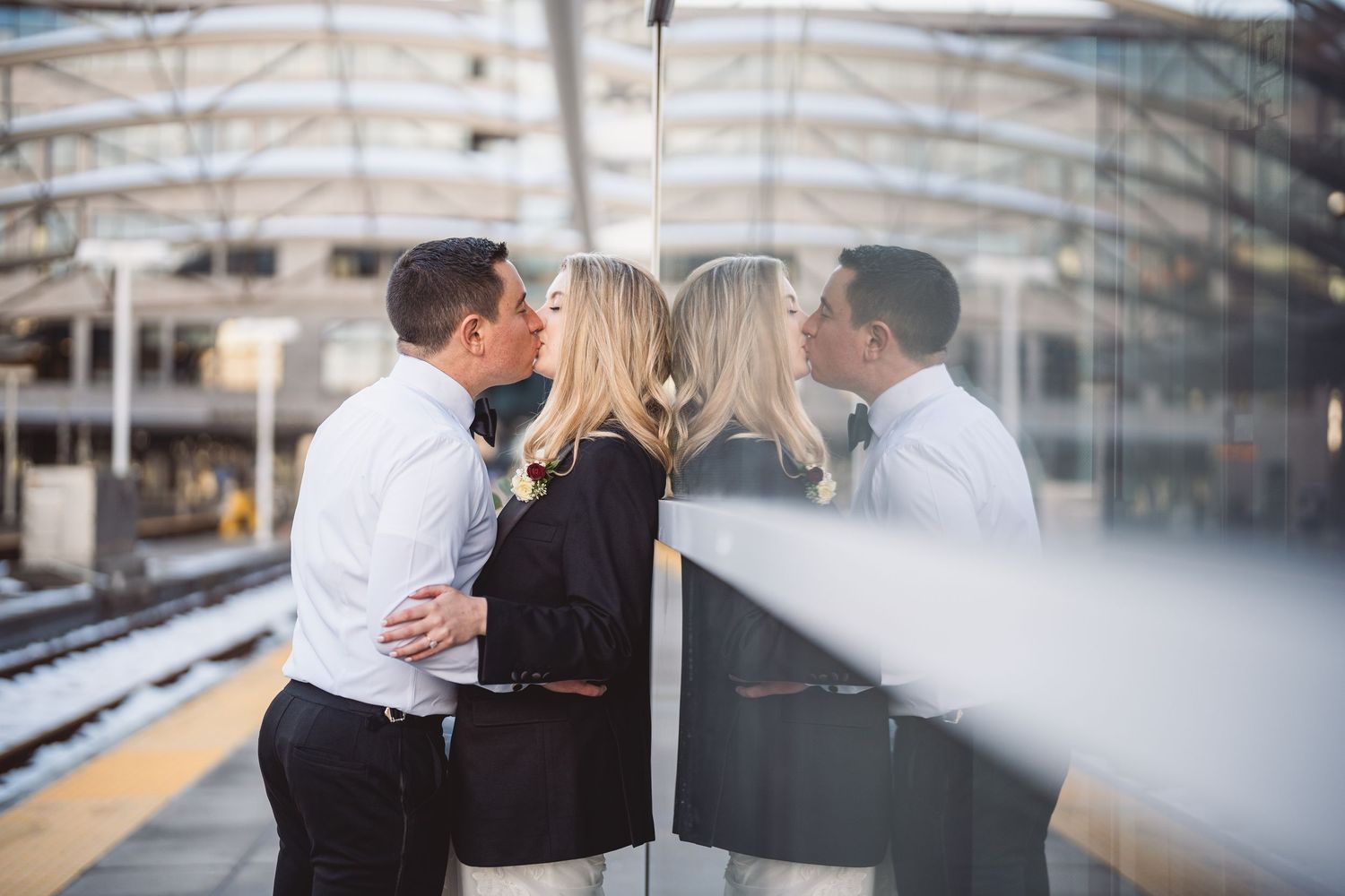 Wedding couple shares intimate moment on industrial train platform.