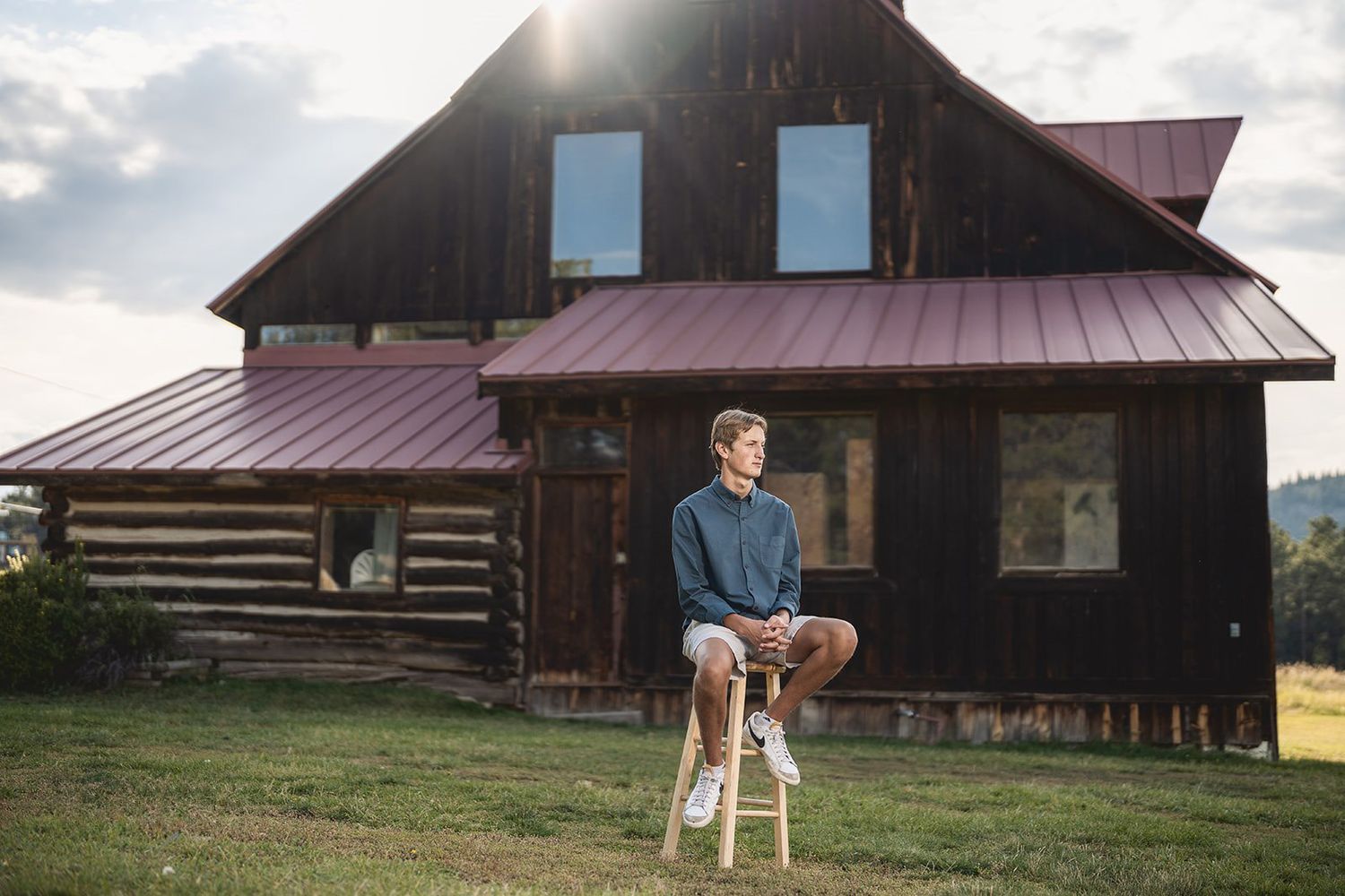 Rustic barn with metal roof against a cloudy sky during golden hour.