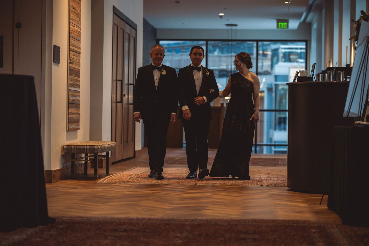 Wedding guests mingle in an elegant venue hallway with modern lighting and decor.