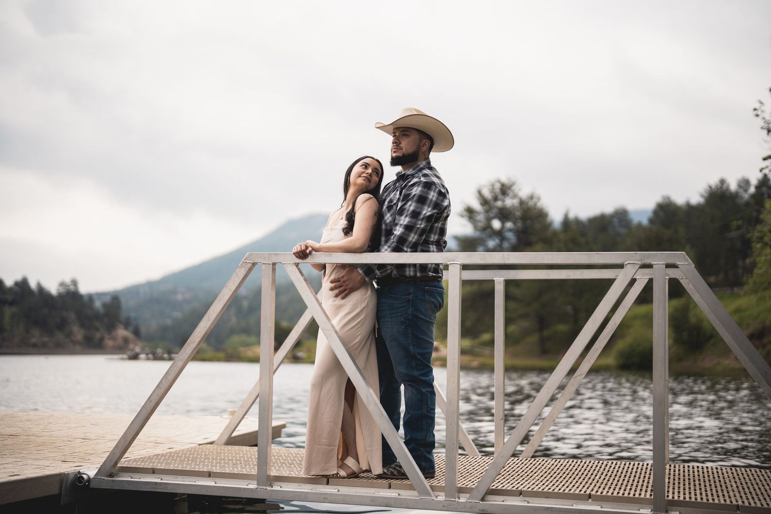 Romantic couple posing by a wooden dock overlooking a scenic lake.