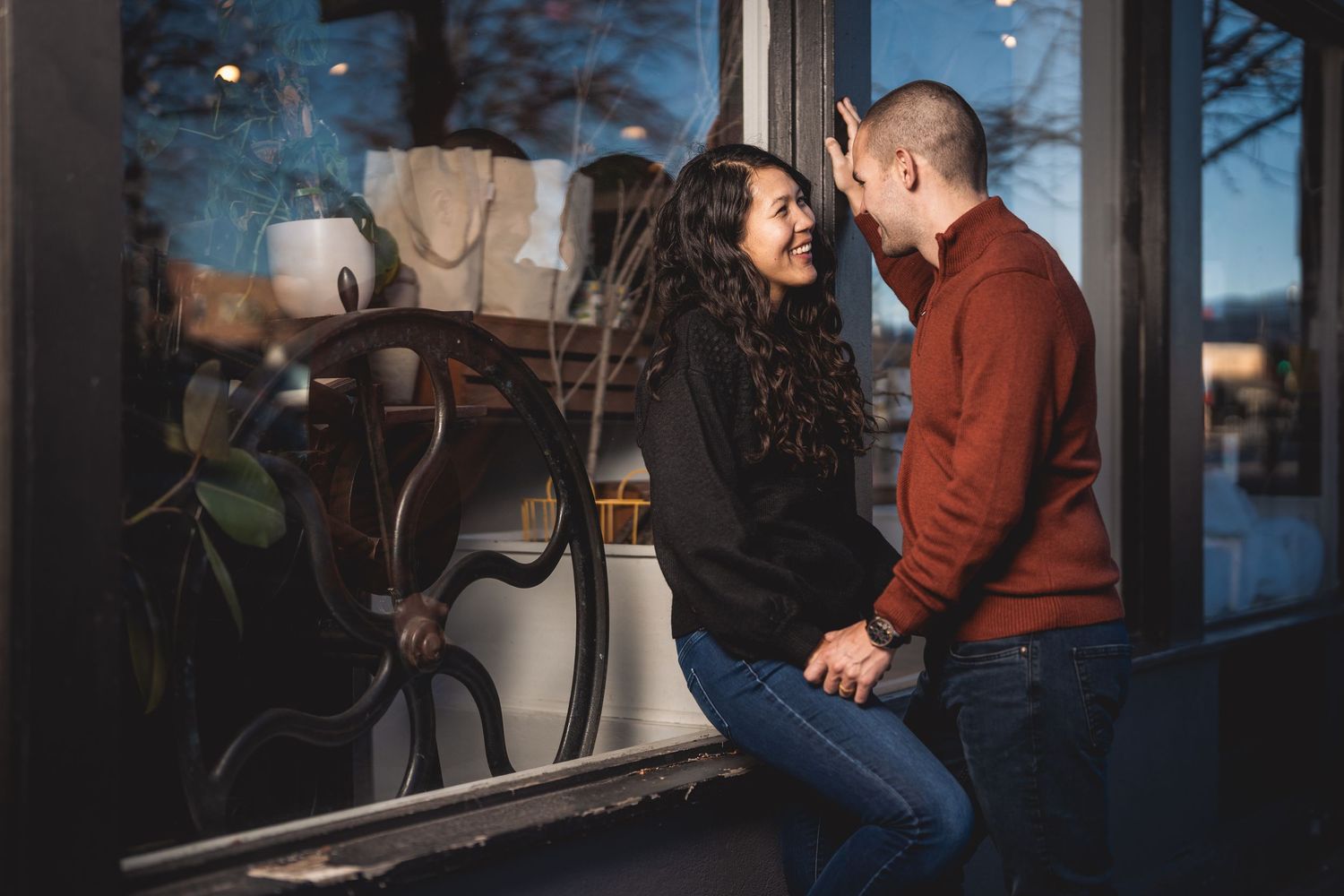 Couple embracing in front of an urban building with dramatic lighting and shadows.