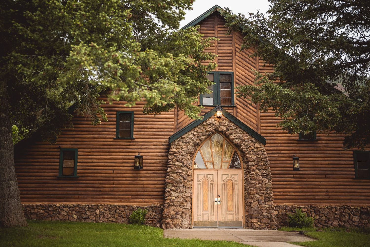 Rustic wooden barn wedding venue with stone archway entrance and natural surroundings.