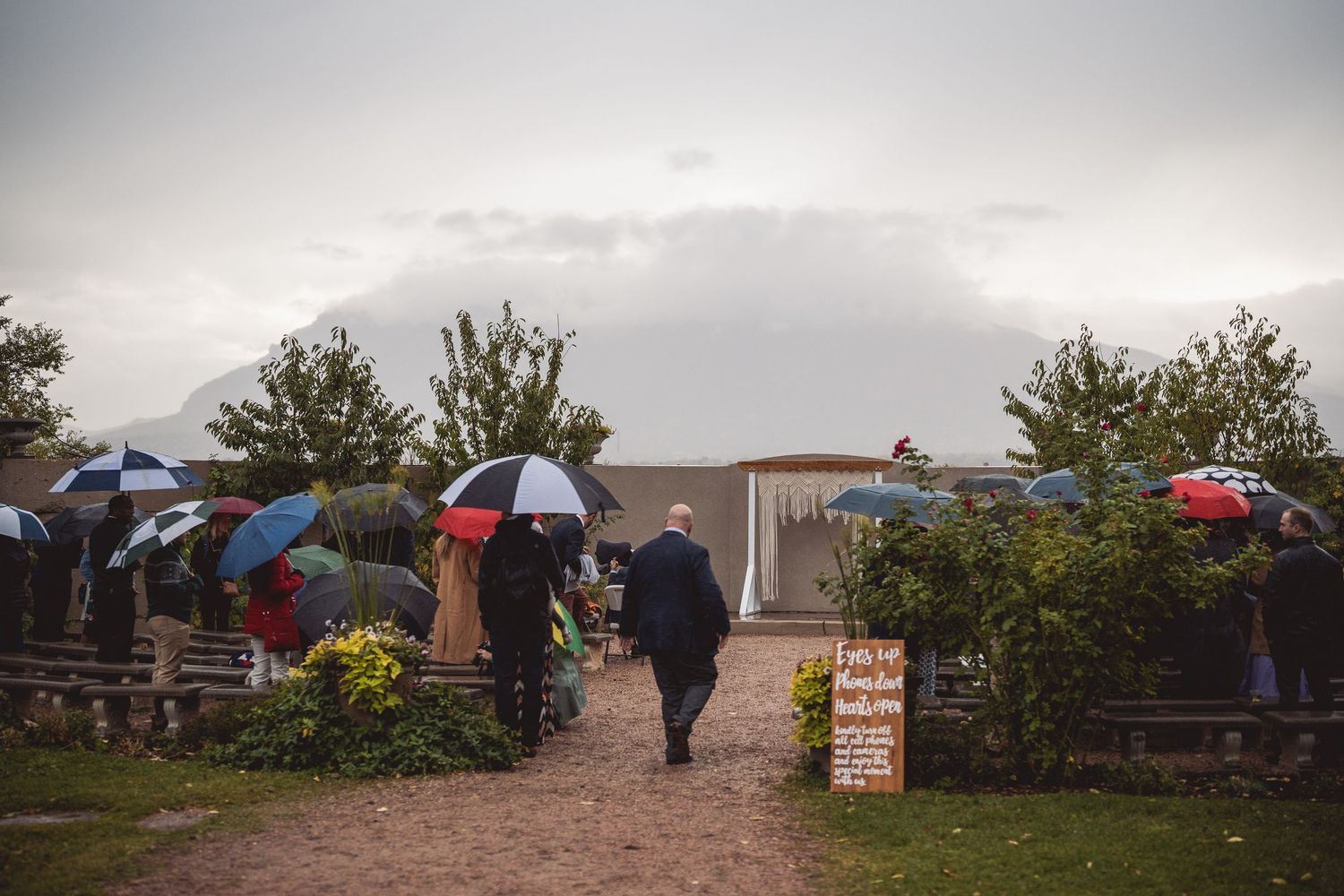 Overcast wedding venue exterior with garden landscaping and gathered guests.