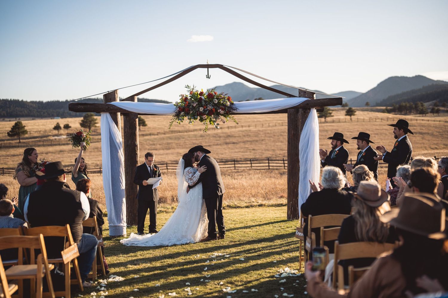 Outdoor wedding ceremony setup with rows of wooden benches against mountain backdrop.