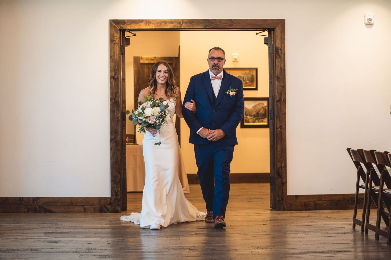 A wedding entrance with a couple walking through a rustic wooden doorframe.