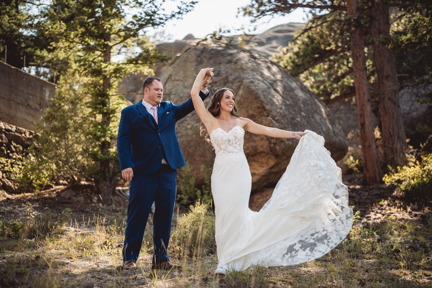 A playful dance moment captured in a natural mountain setting with pine trees.