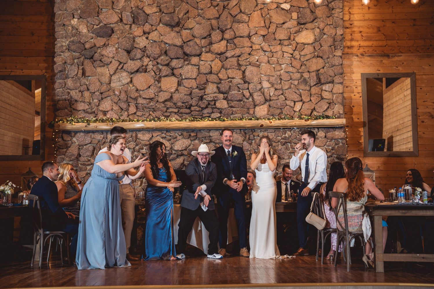 Wedding reception in a rustic stone-walled venue with string lights overhead.