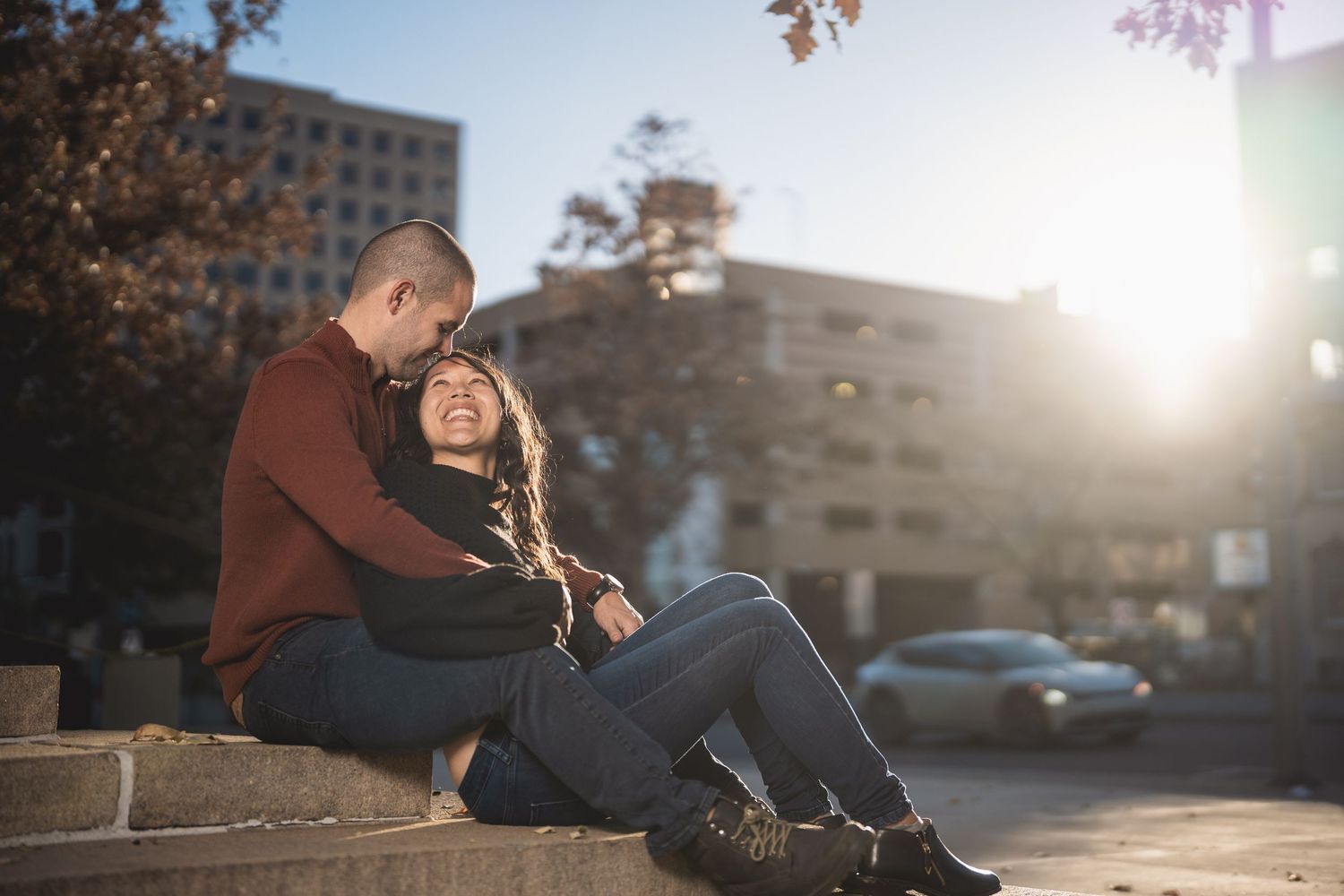Couple sitting together on steps during golden hour in an urban setting.