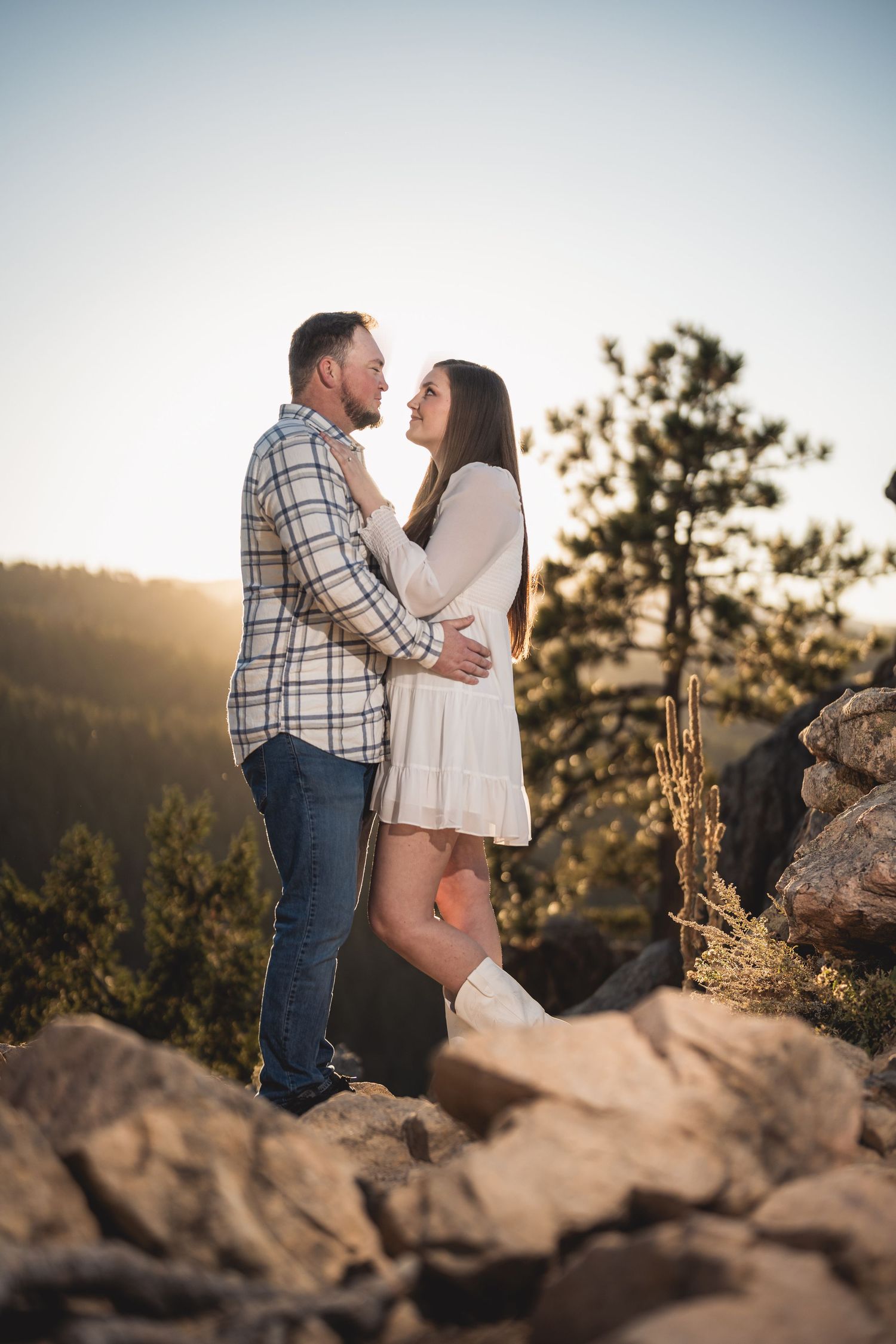 Romantic mountain top engagement session at sunset with couple on rocky terrain.