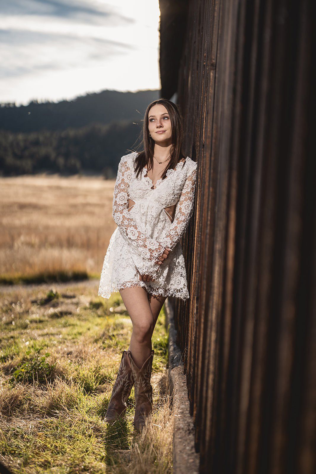 Fashion portrait against rustic wooden posts in a countryside setting.
