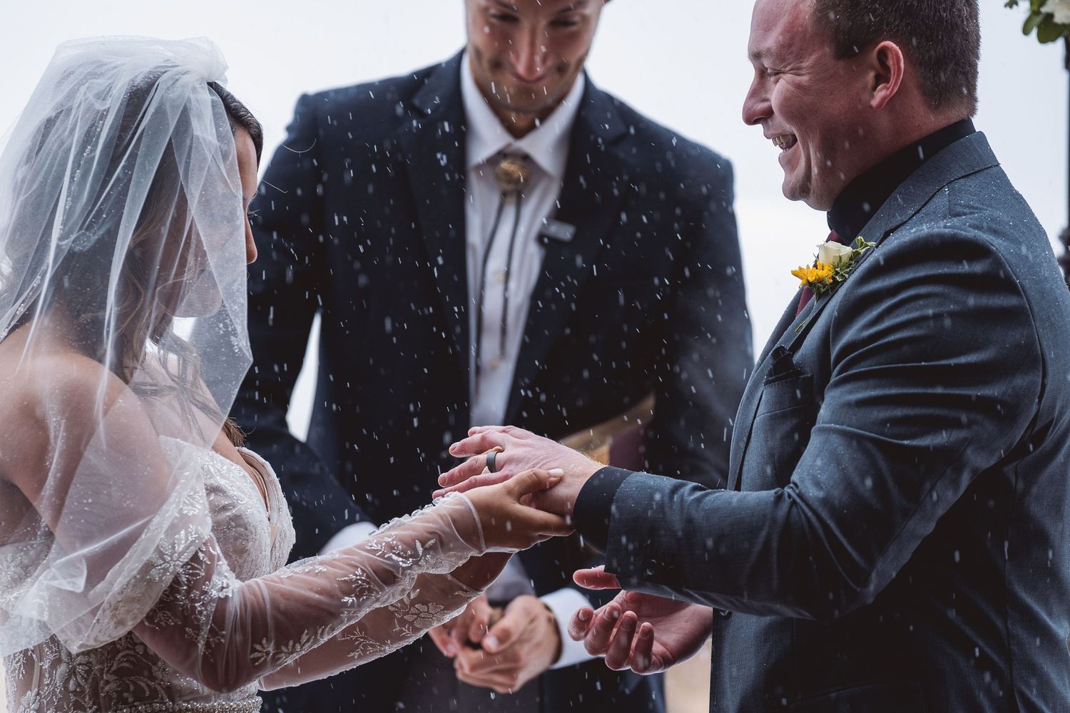 A wedding ceremony moment in the rain with exchanging of rings.